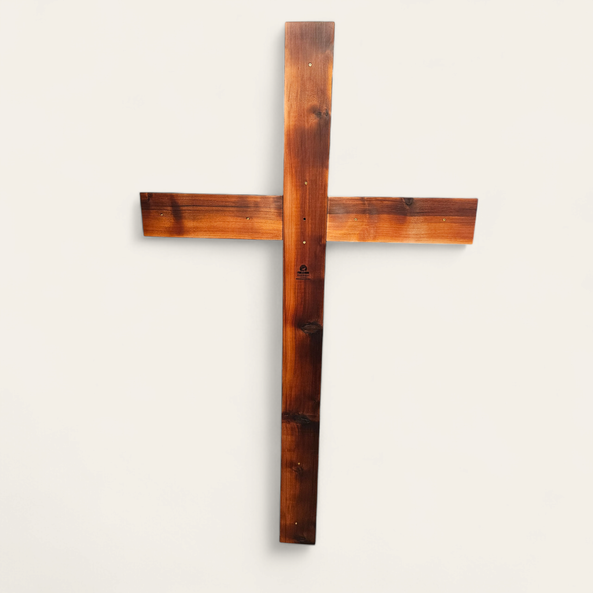 A wooden wall cross mounted on a plain white wall.