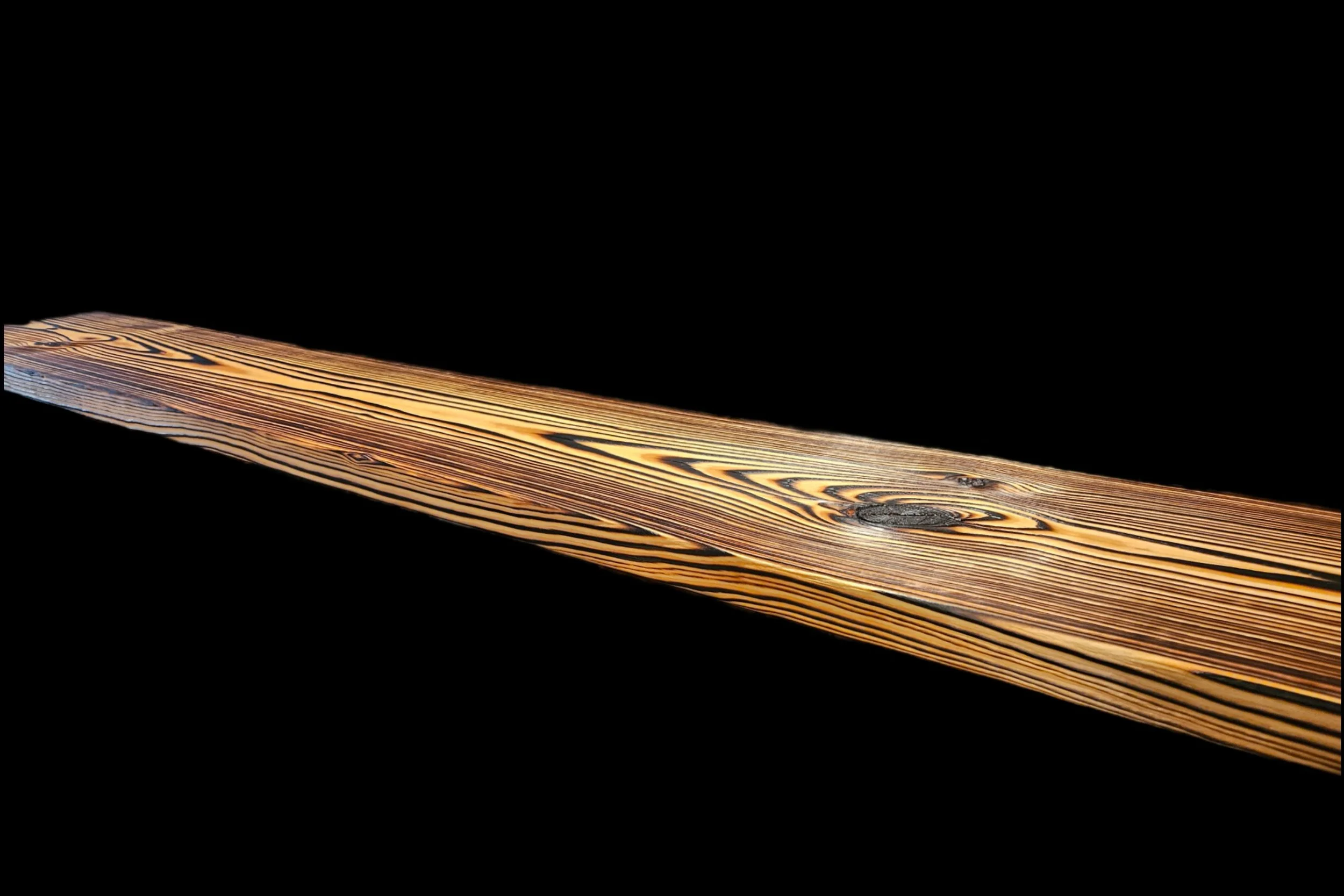 Close-up of a wooden plank with visible grain and knots against a black background.