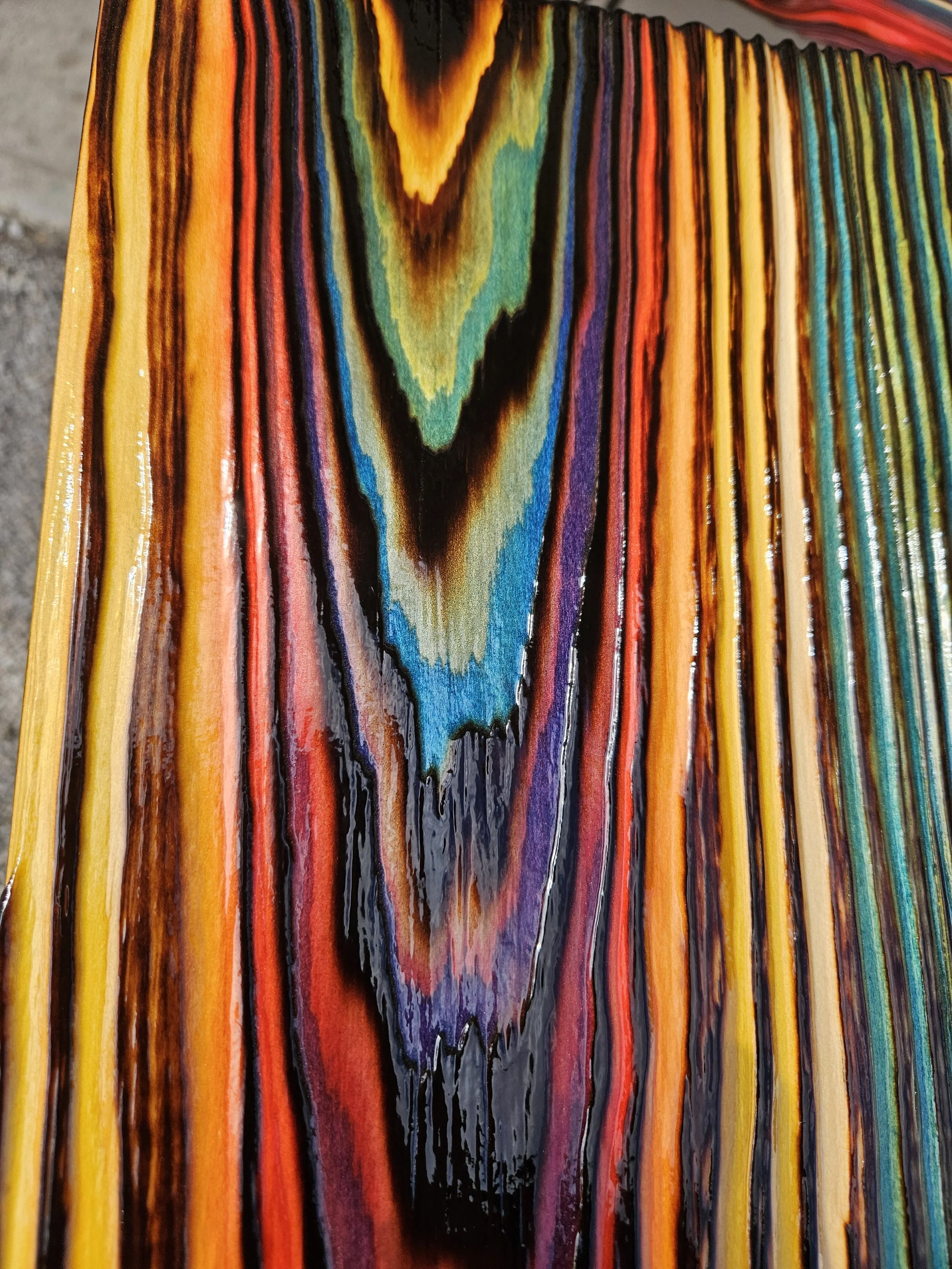 Close-up of a wooden surface with multicolored, rainbow-like streaks and a prominent dark jagged line running vertically down the center.