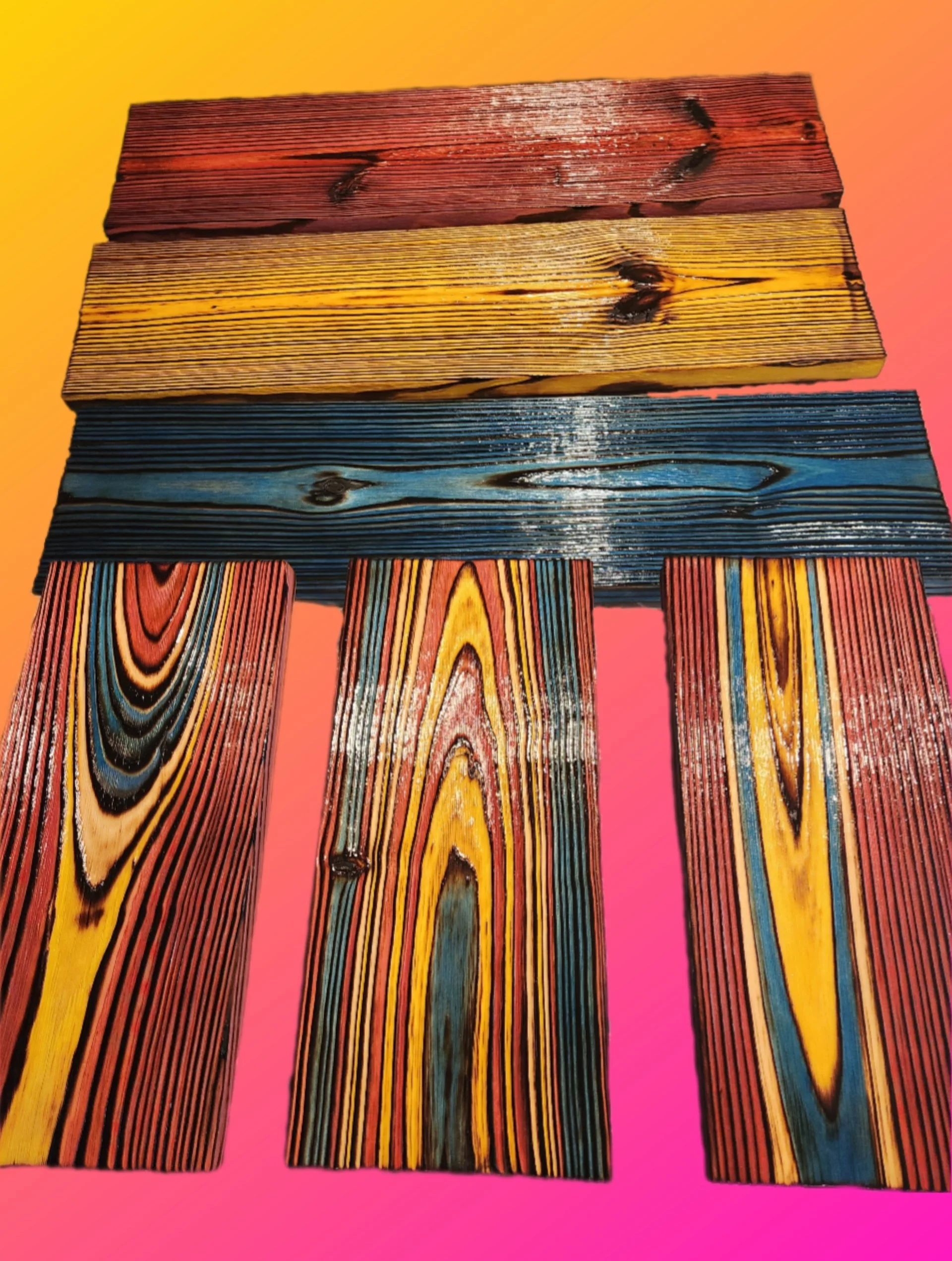 Close-up of colorful painted wooden planks arranged vertically on a pink background.