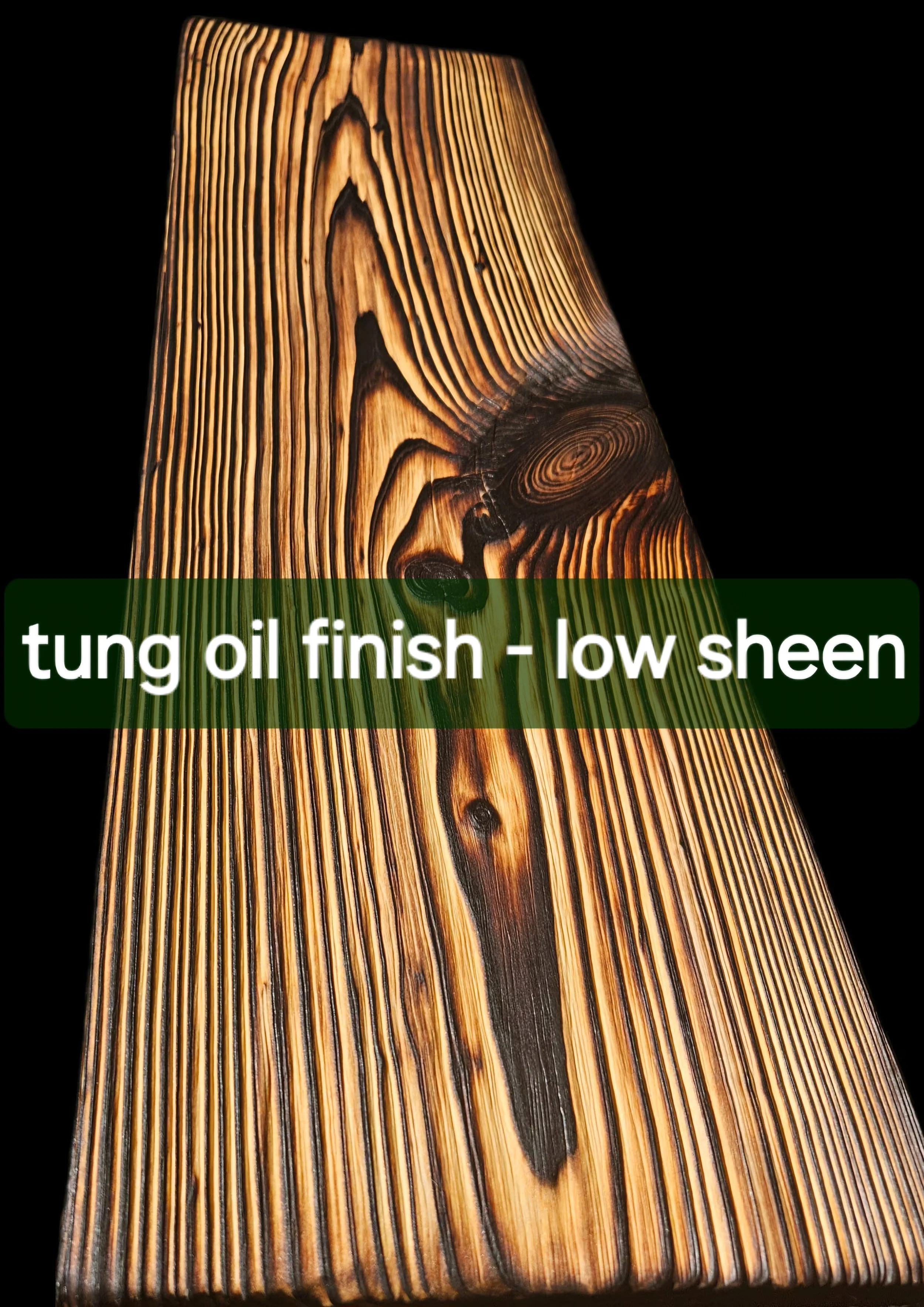Close-up of a piece of wood with a tung oil finish, showcasing its natural grain and knots, against a black background.