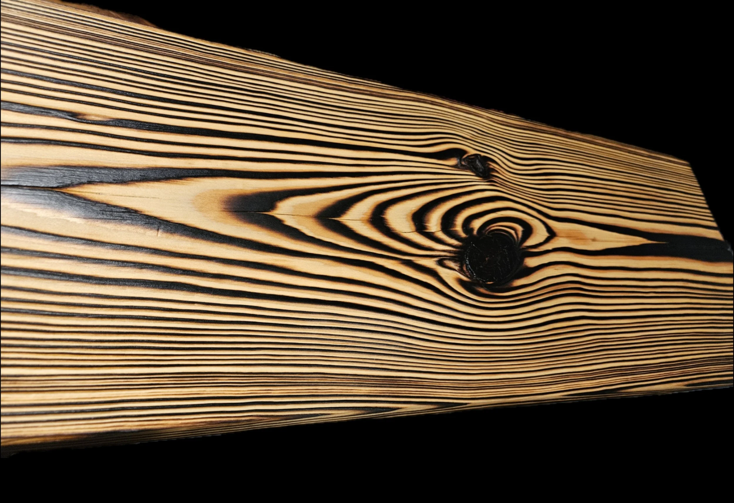 Close-up of the pages of an open, well-worn book with visible wood grain-like patterns on the edges of the pages and darkened edges from aging.