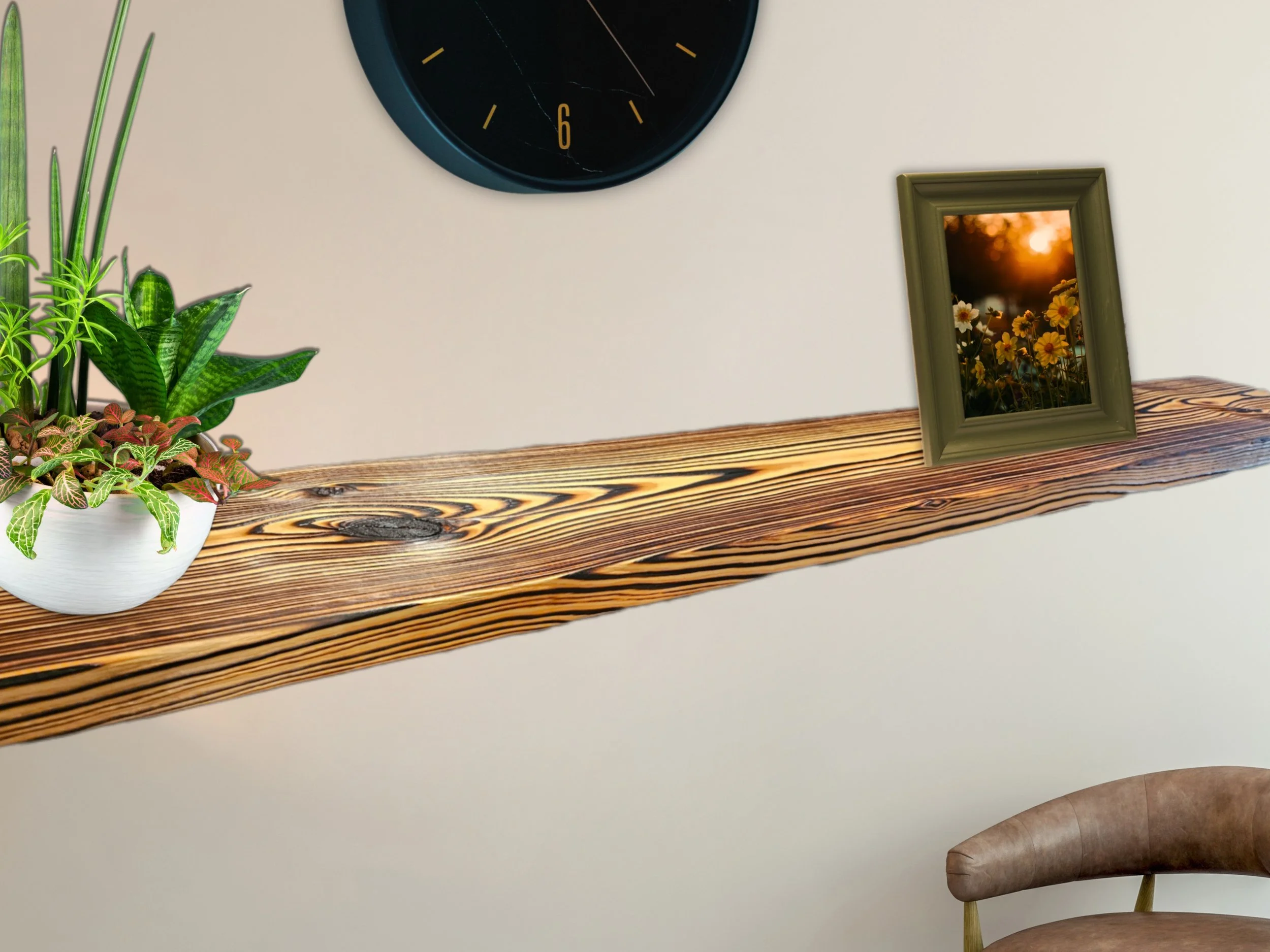 A minimalist interior with a wooden shelf holding plants, a framed sunset photograph of flowers, and a black wall clock with gold markings, all against a beige wall.