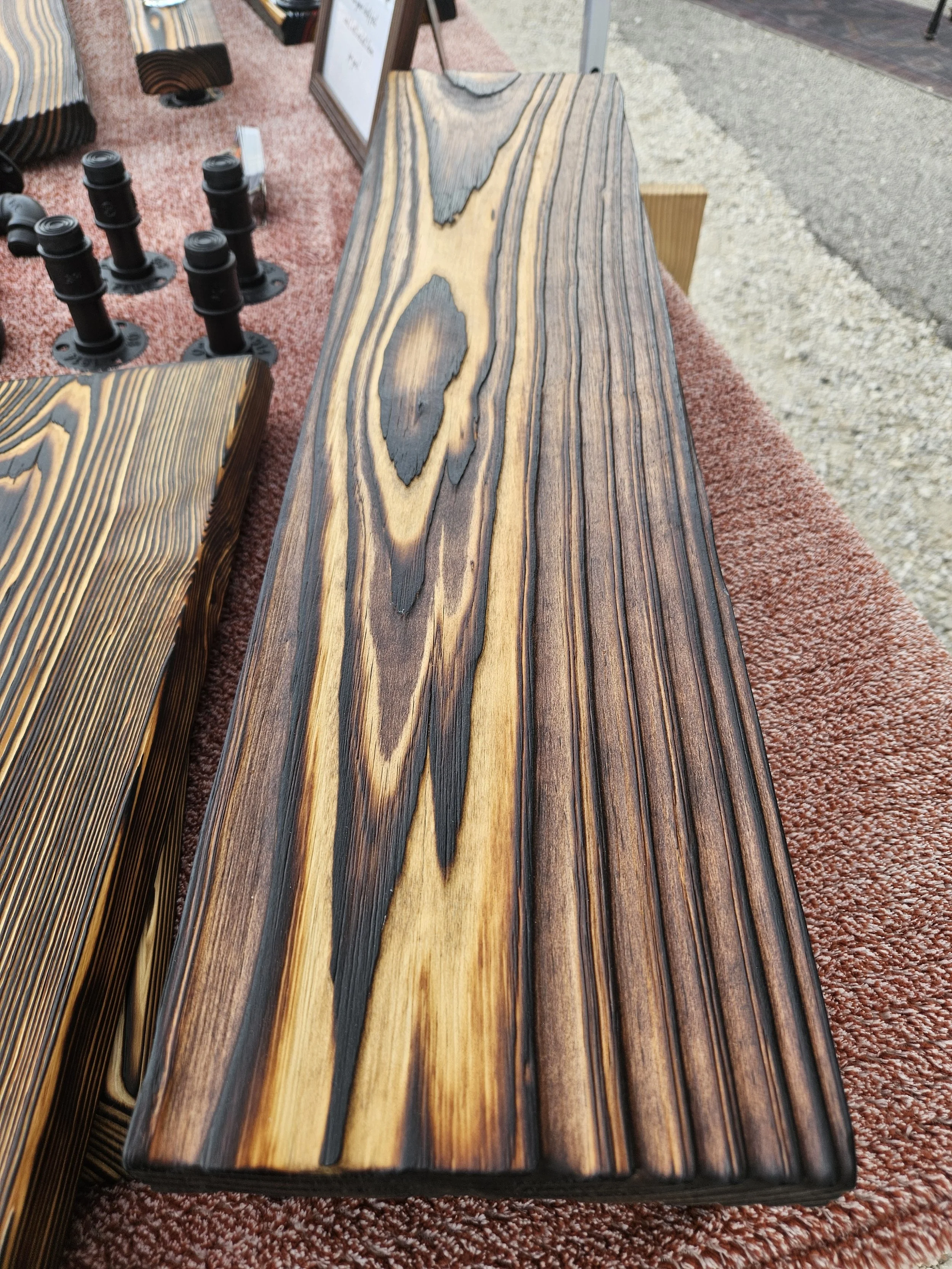 Close-up view of a wooden table with a distinctive grain pattern, displayed at an outdoor market or exhibit.