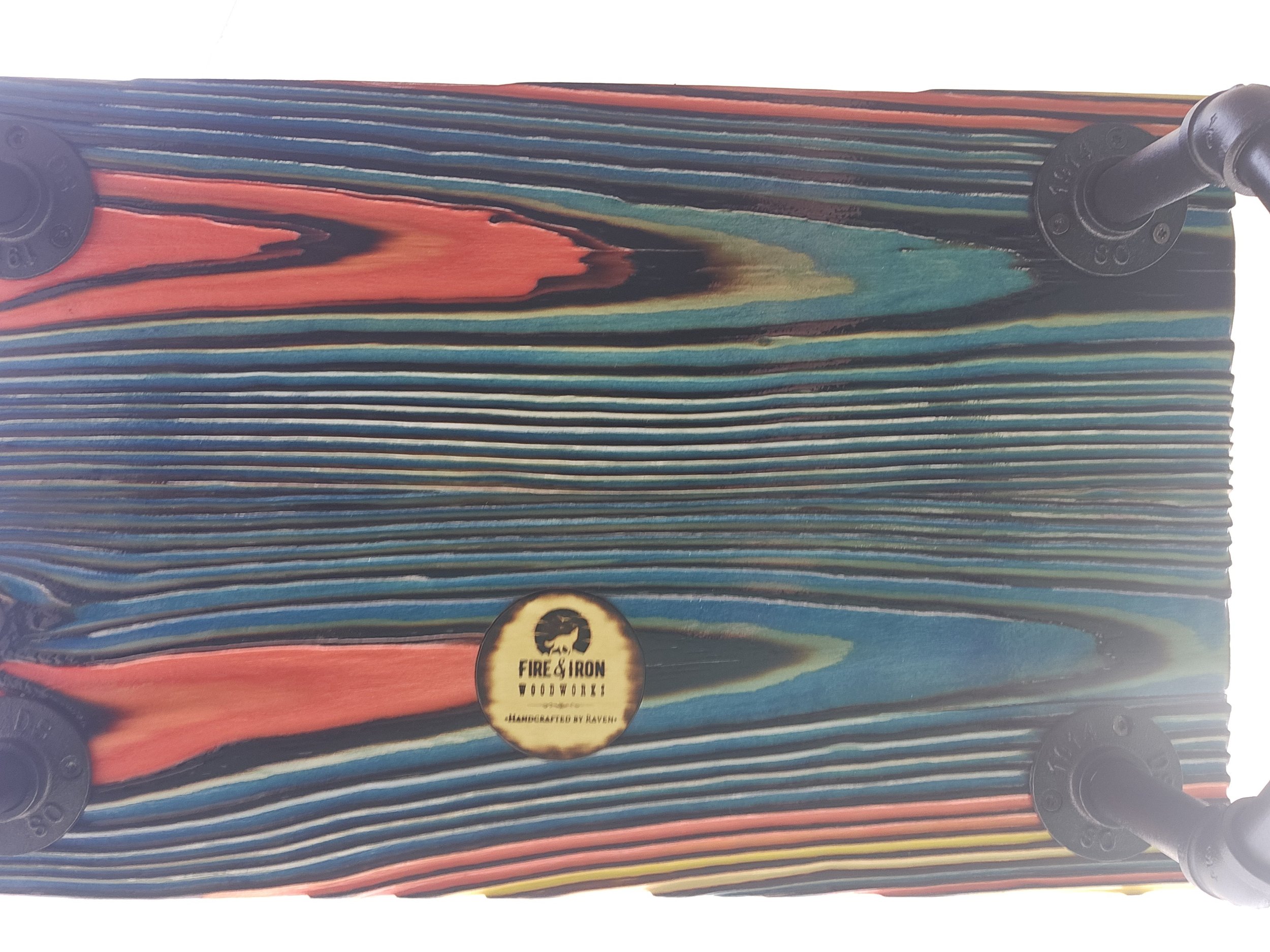 A stack of colorful wooden fire paddles with a label that says 'Fire & Iron Woodwork, Handcrafted by Raveh'.