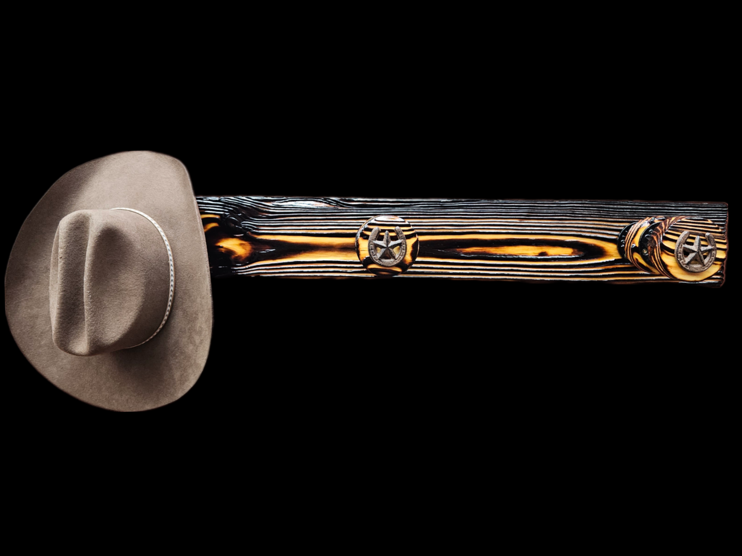 Beige cowboy hat with a white band and decorative conchos resting on a dark wood bench with burnt edges and black background.