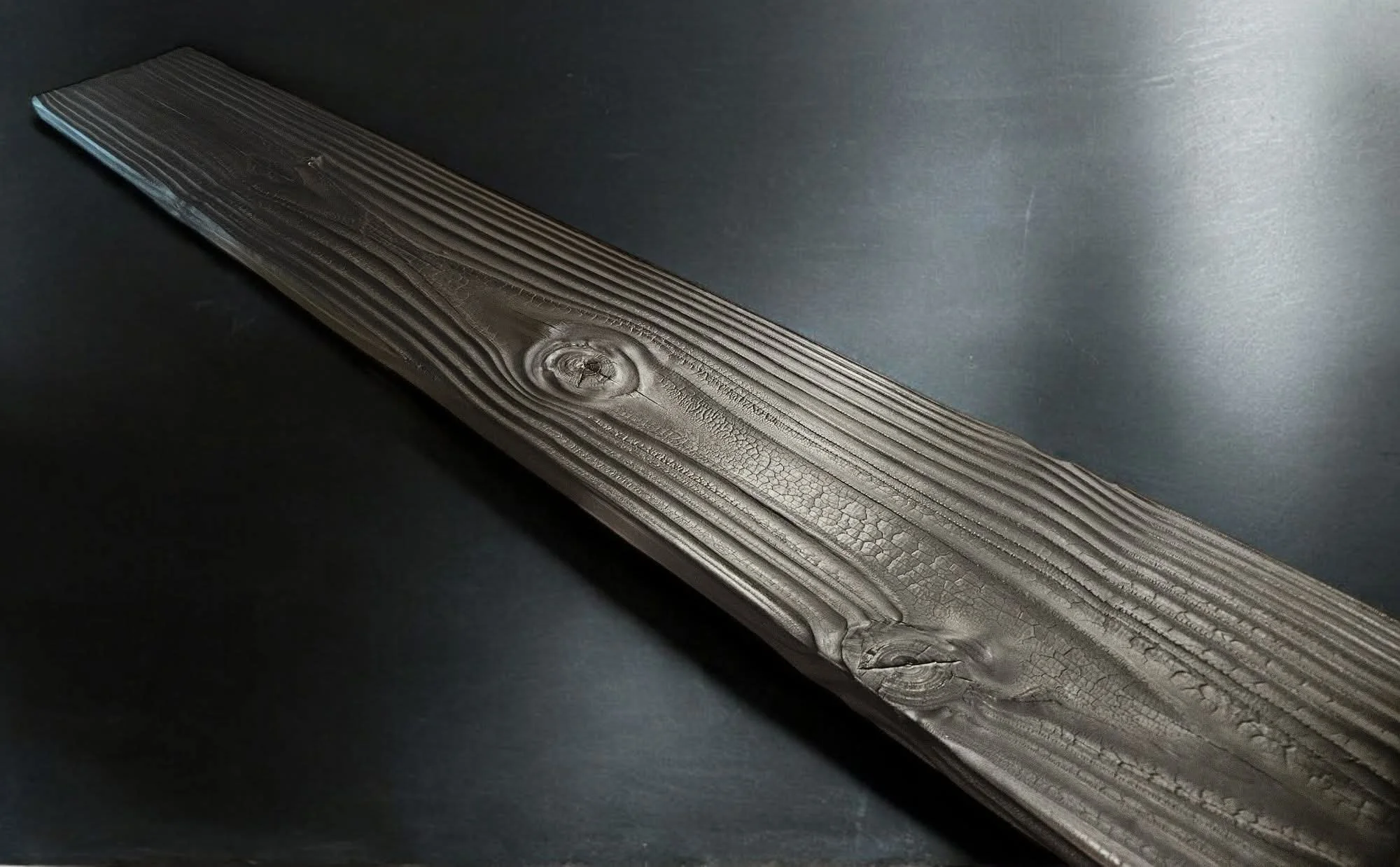 Close-up of a dark FireForged™ wood edge showing natural grain and a hand-finished surface.