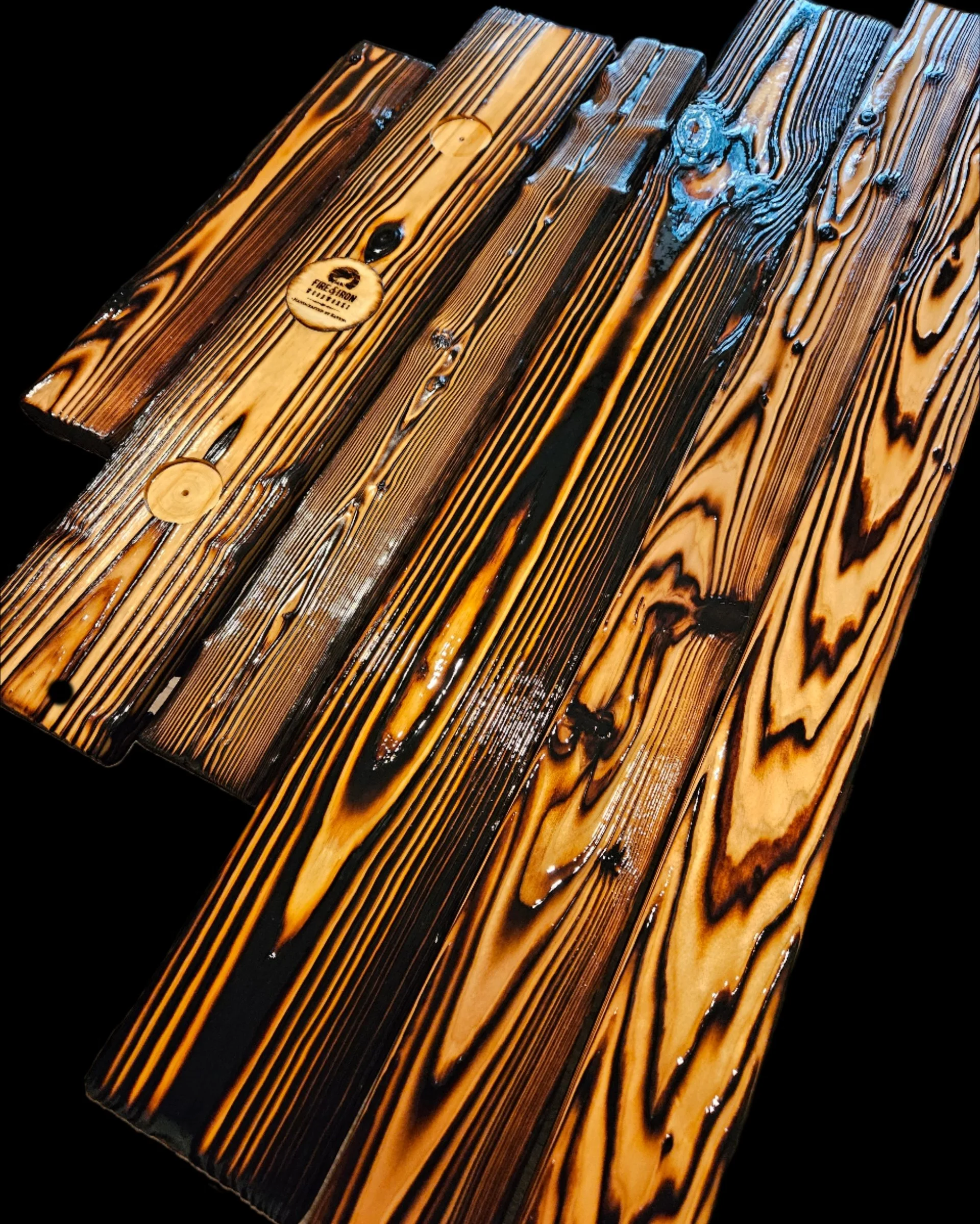Close-up photo of a wooden surface with dark lines and knots, coated with a shiny finish, against a black background.