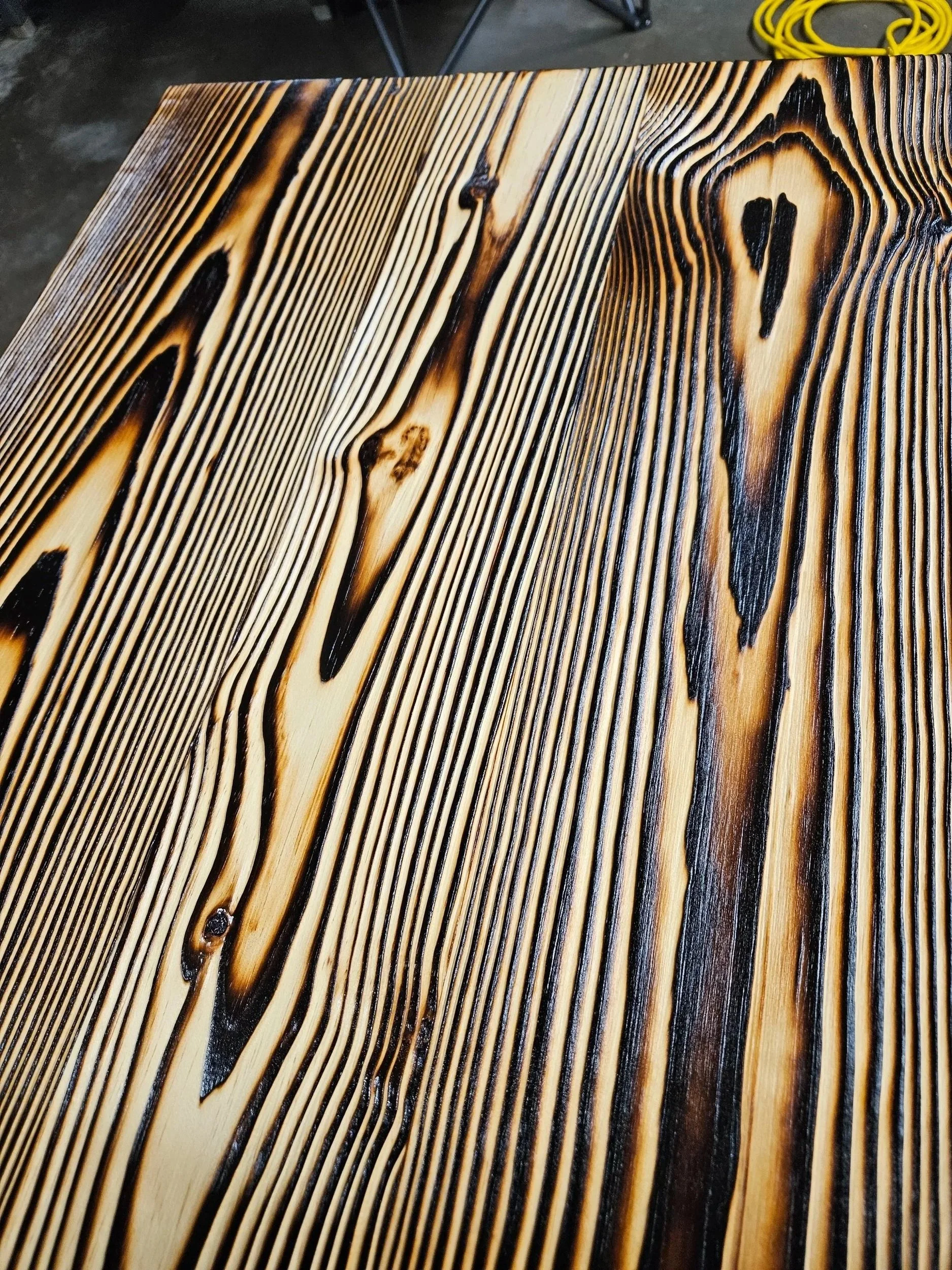 Close-up of FireForged™ wood showing raised grain and dark lines revealed by fire.