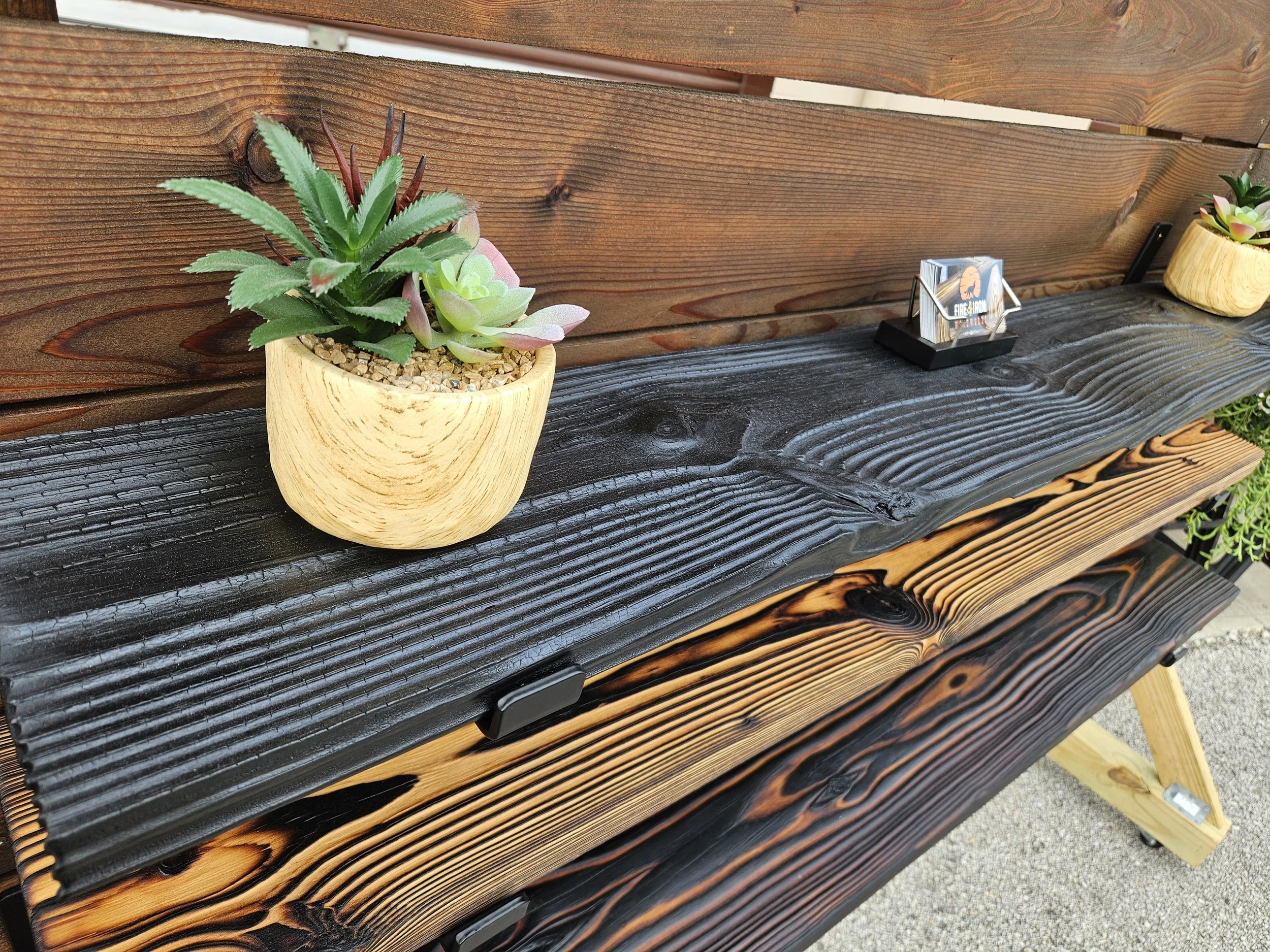 Wooden countertop with potted succulents and a small cardholder.