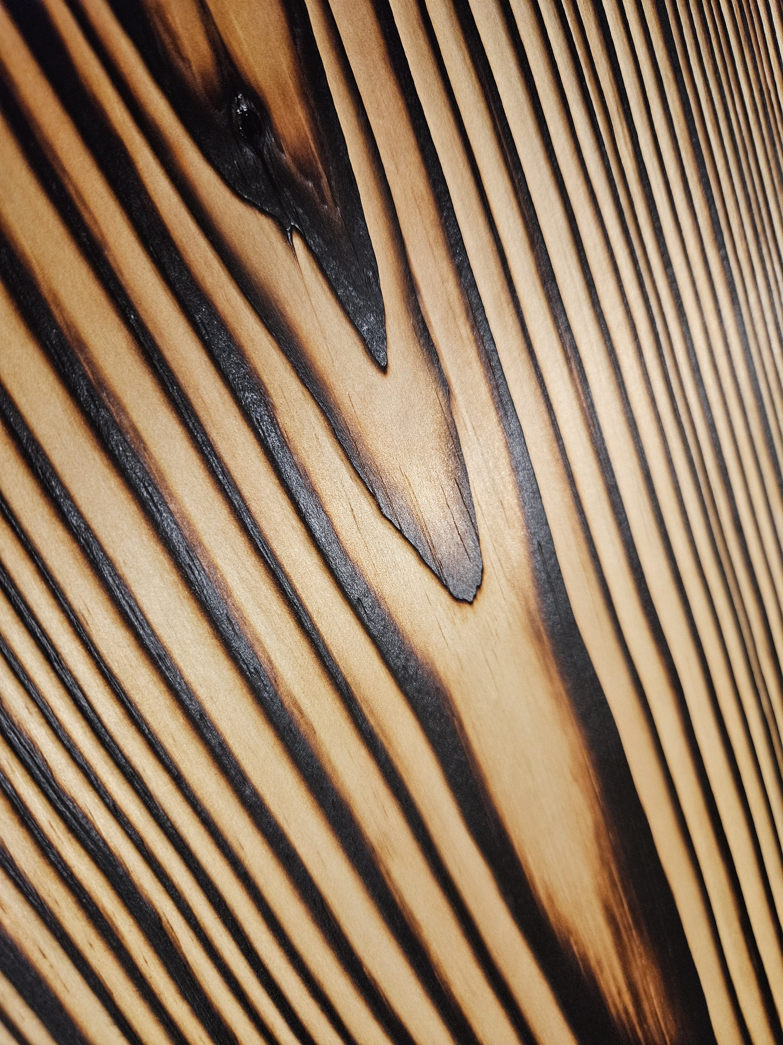Close-up of a wooden surface with black grooves and a crack with dark resin in the center.