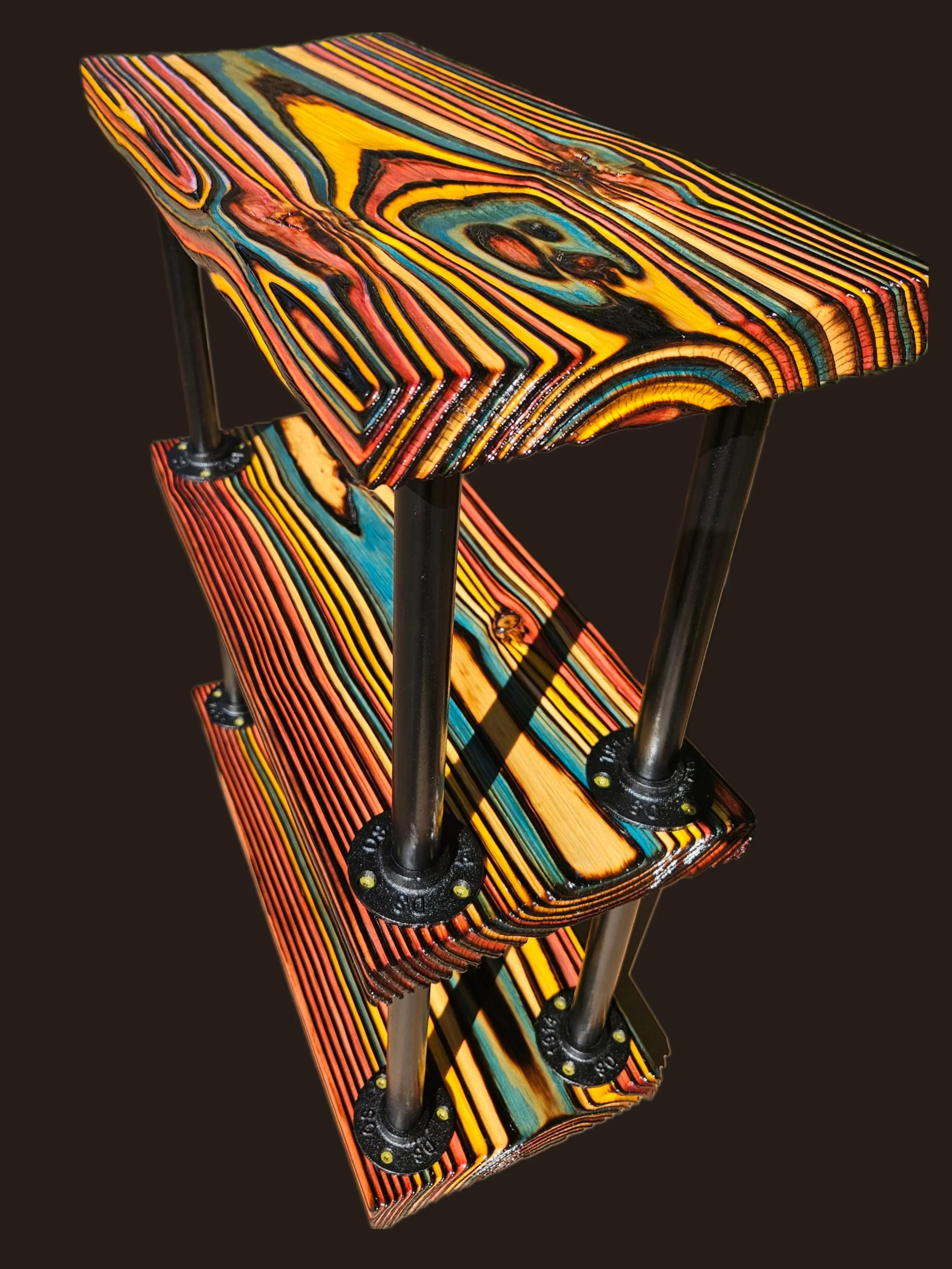 Colorful wooden stool with a mosaic pattern of vibrant rainbow colors including yellow, orange, red, blue, and black, supported by black metal legs.