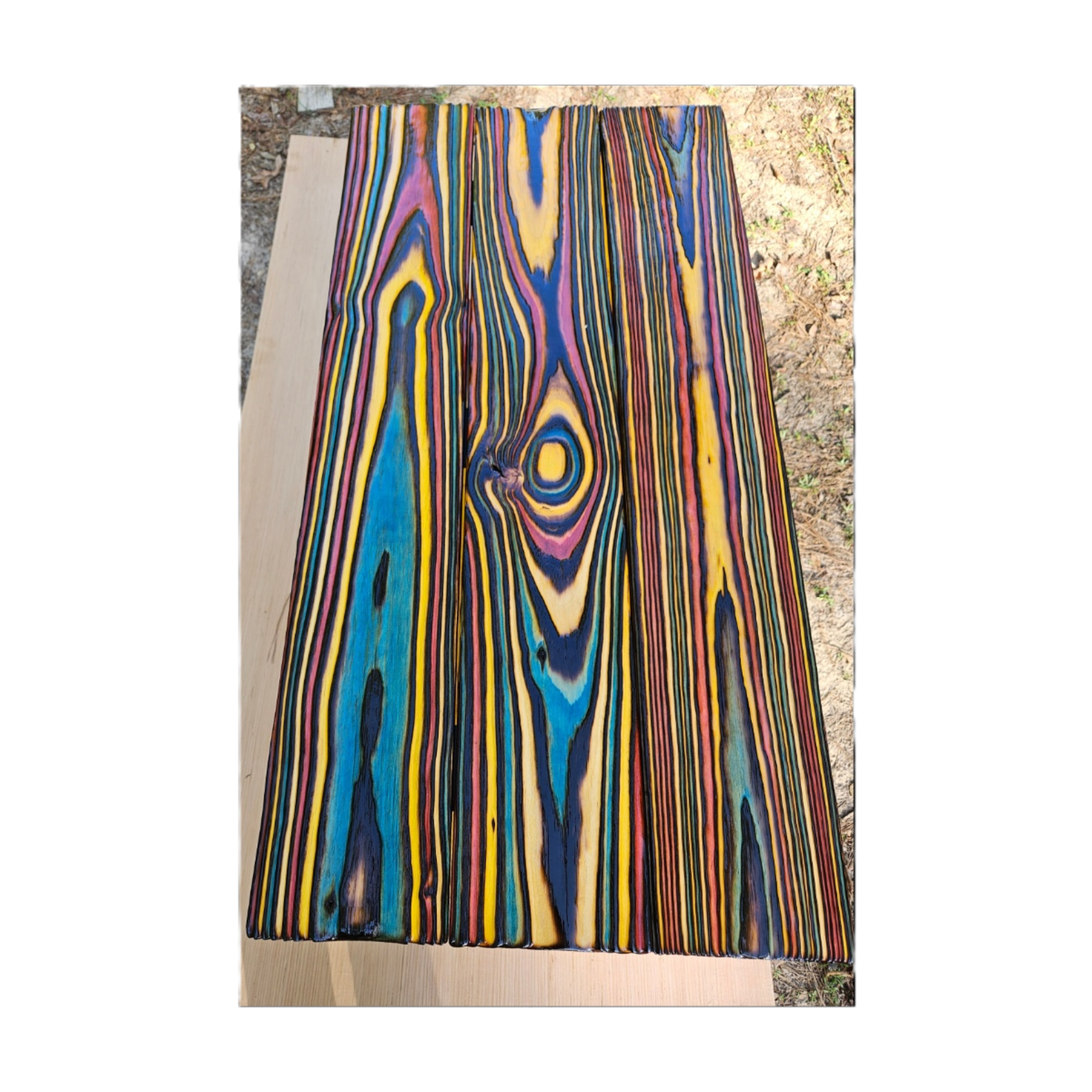 Colorful wood planks with vibrant, swirling paint designs placed outdoors on a wooden surface.