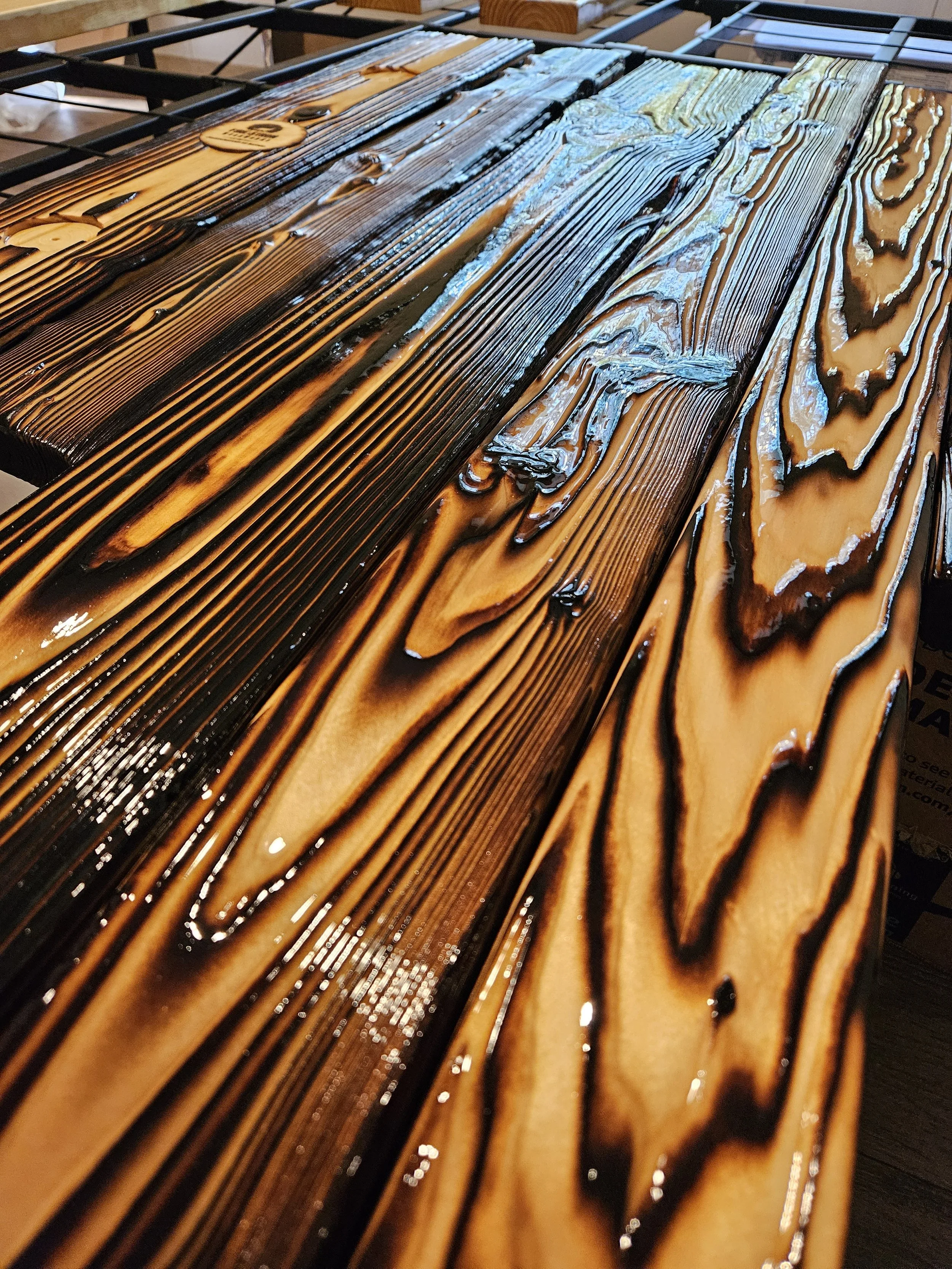 Close-up of a wooden slatted table with a shiny, polished surface, featuring dark and light brown streaks and grains.