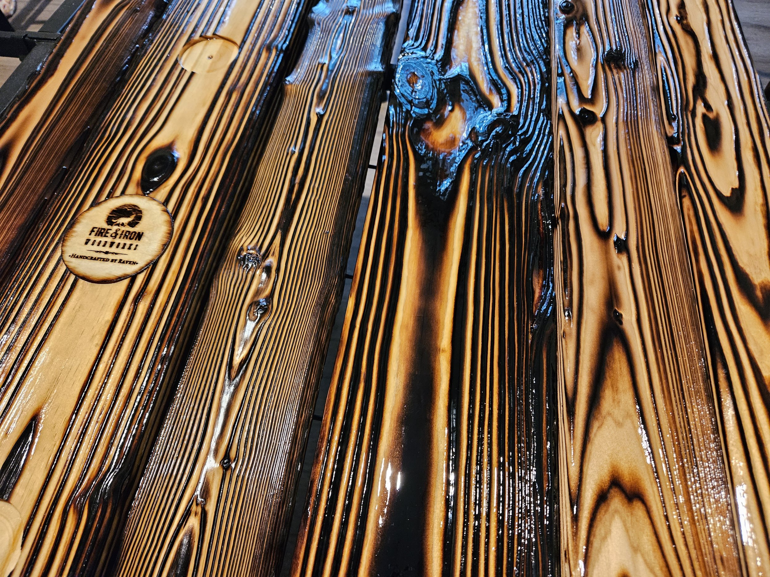 Close-up of a glossy FireForged™ surface with blue accents and the Fire & Iron maker’s mark.