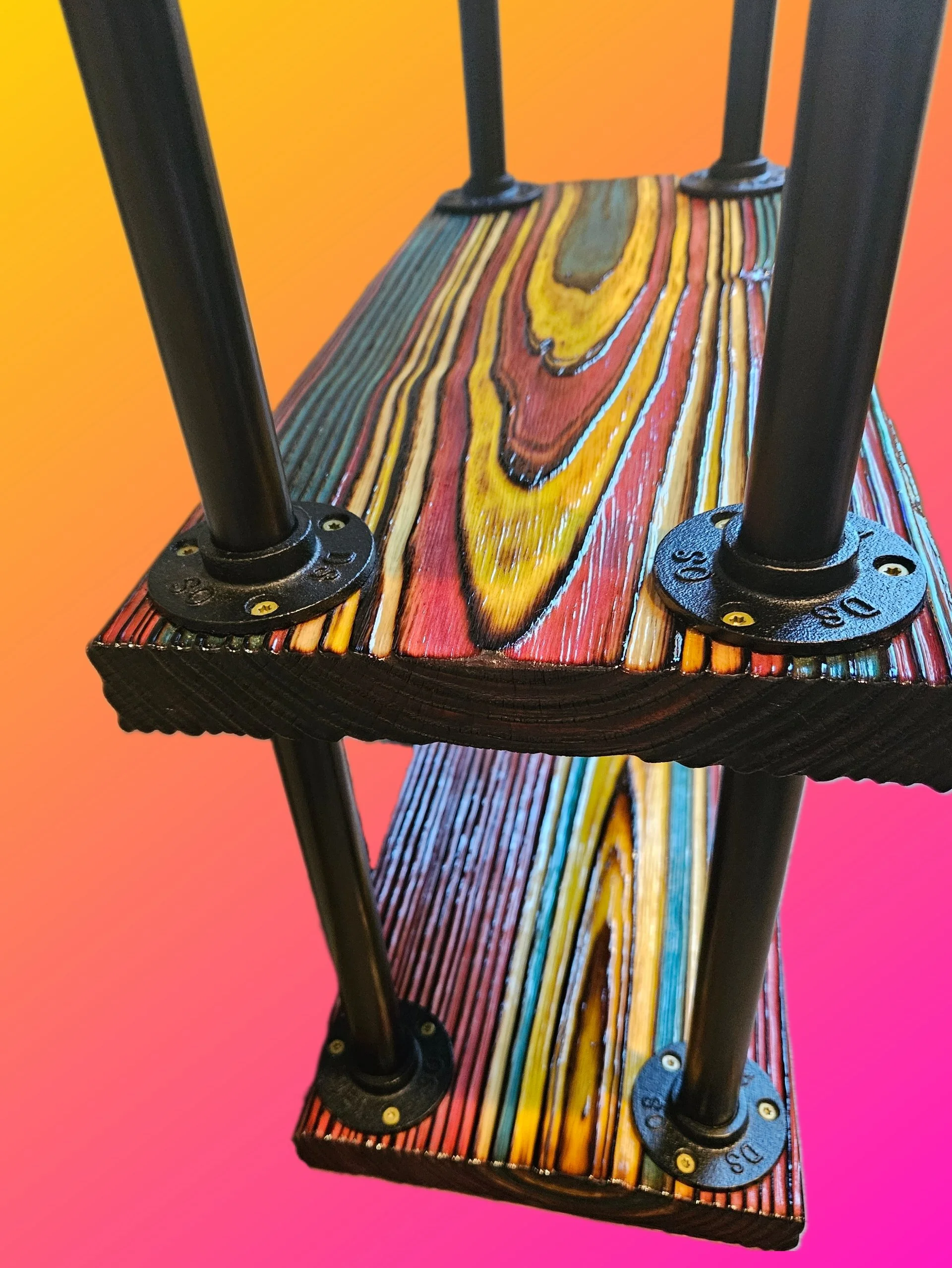 Close-up of a wooden shelf with black metal supports against an orange and pink background.