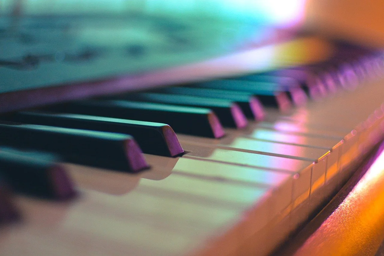 Close-up of piano keys with colorful lighting.