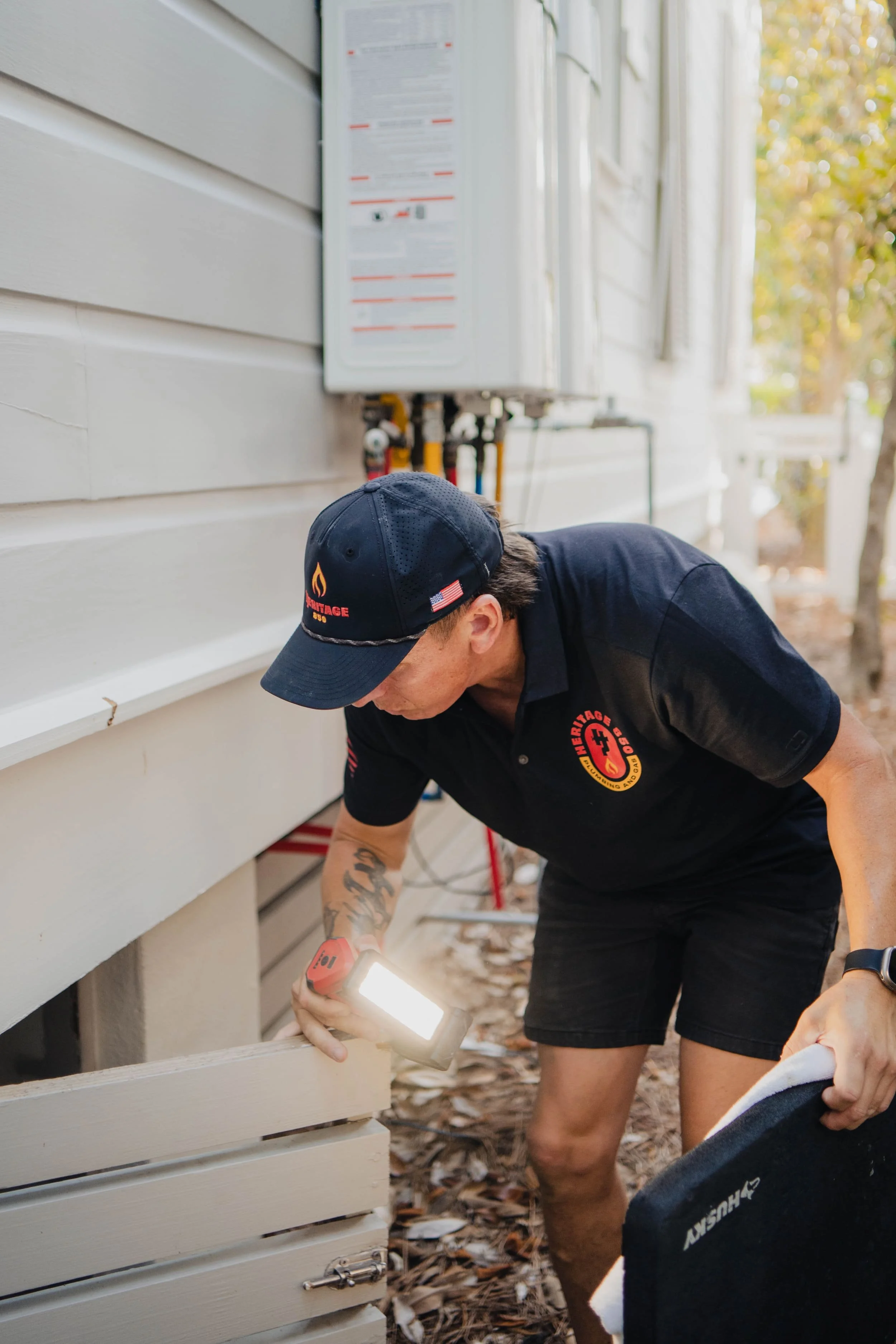 plumber using a flashlight and checking for leaks