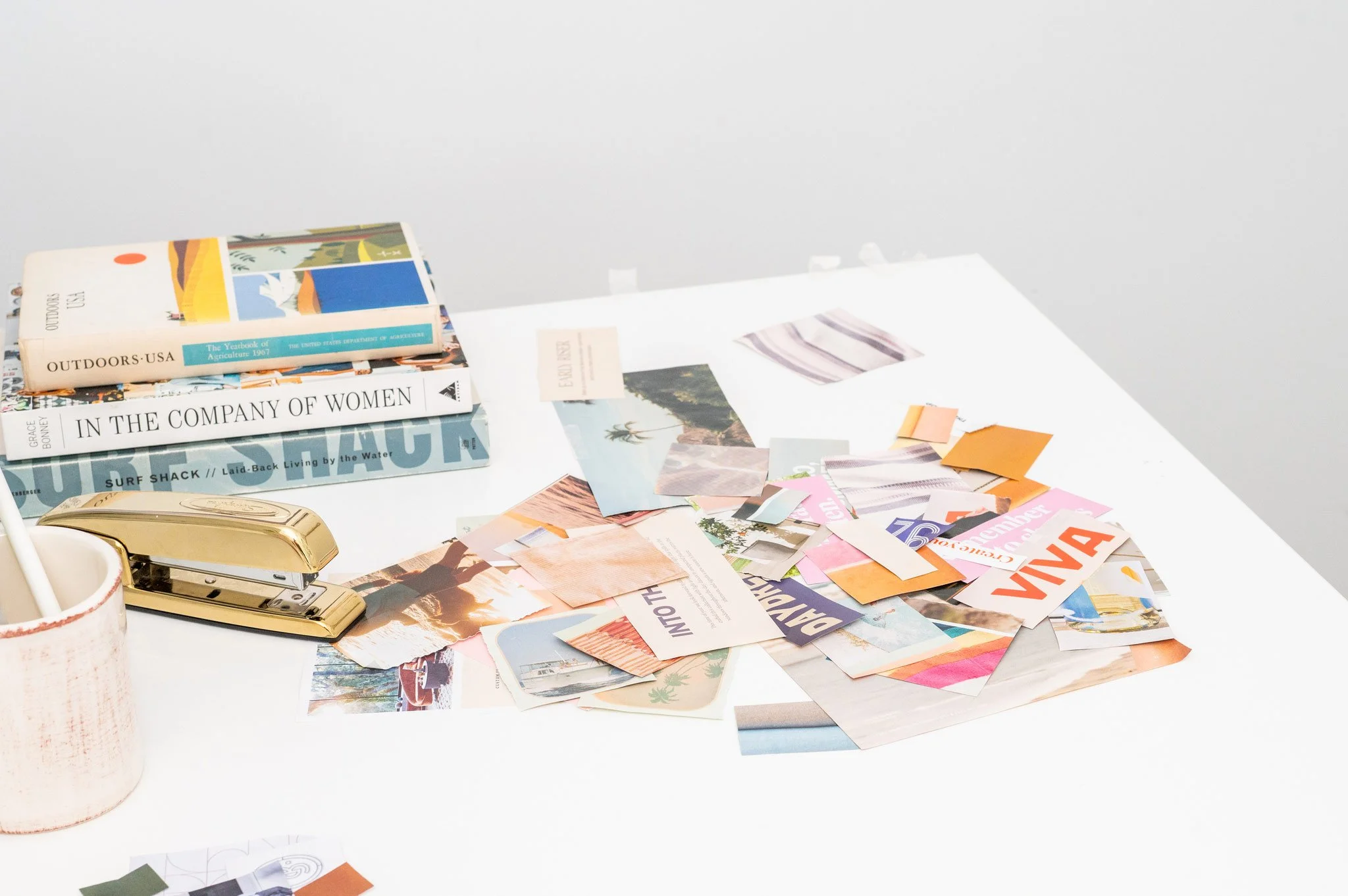 Little Orange Studio design inspiration — books, magazine clippings, and collage materials on a studio desk