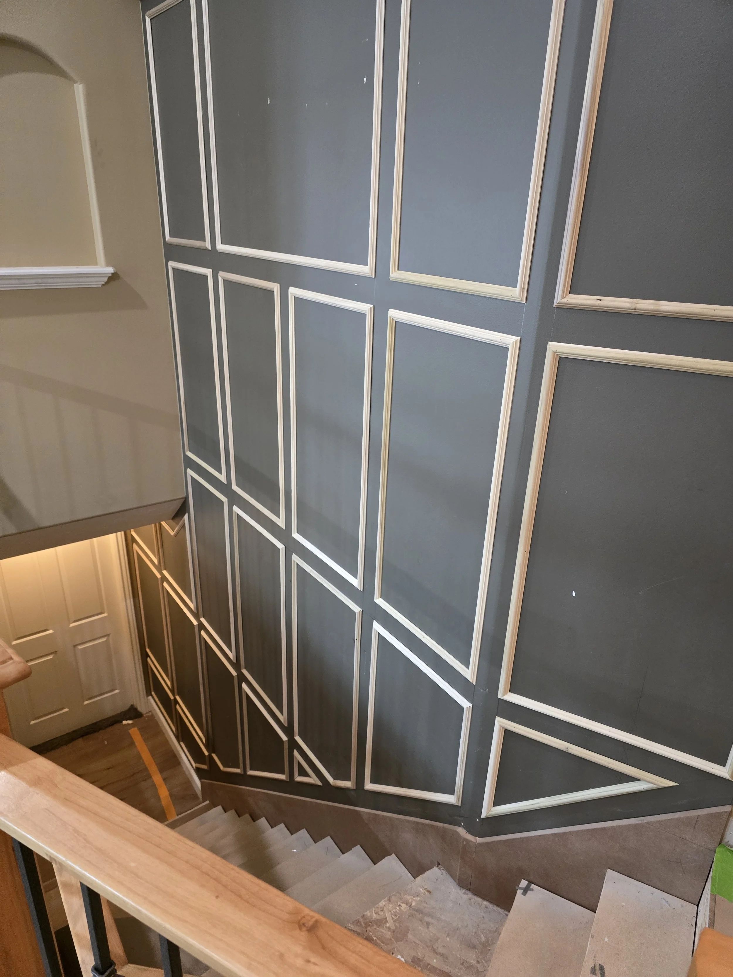 Custom picture frame moulding accent wall following a staircase in a Utah home. Each panel was individually laid out to match the changing angles of the stairs while maintaining visual balance throughout the design.