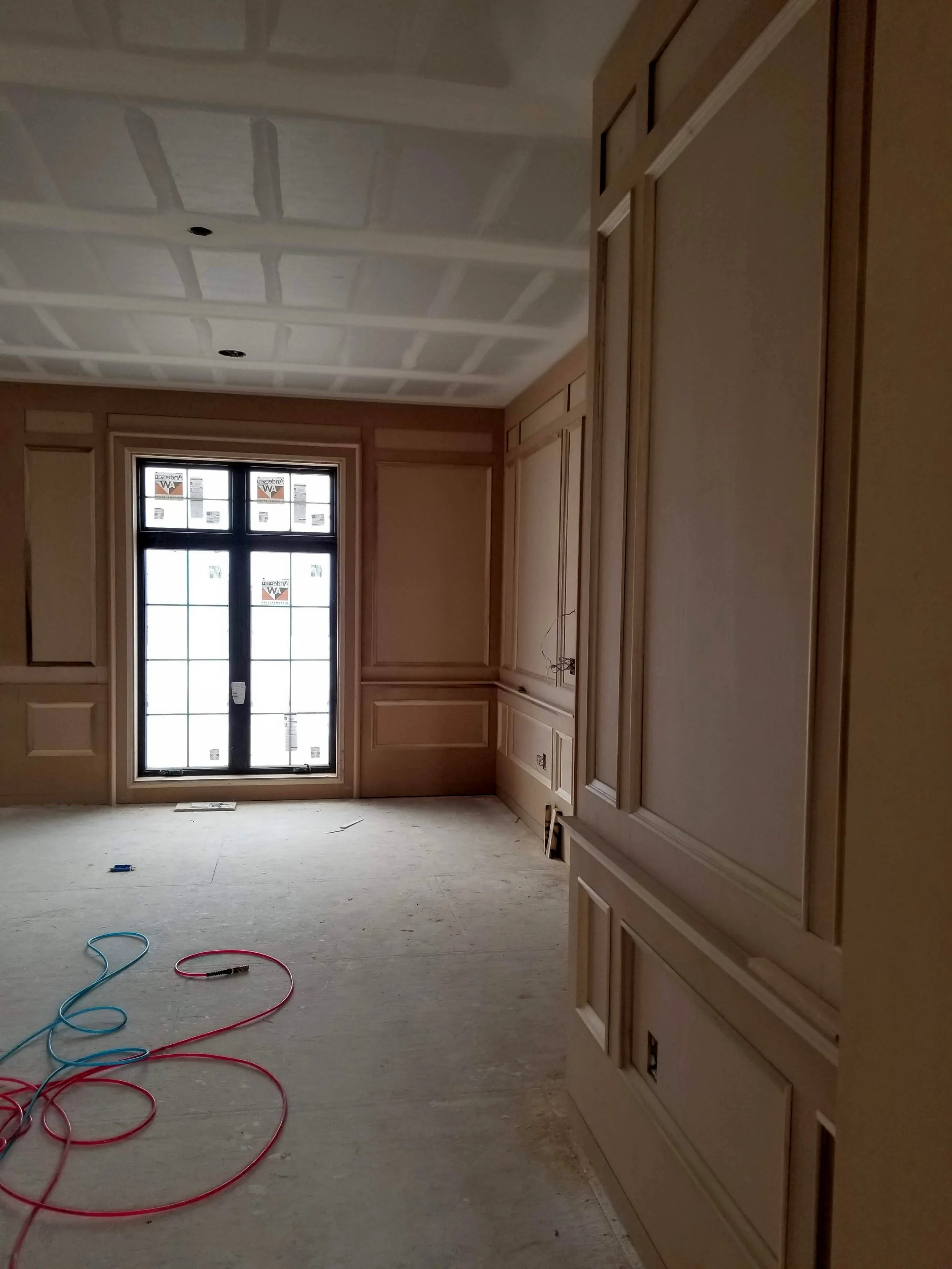 Custom wall moulding and coffered ceiling installation in progress by CBR Interiors in a Utah home. The trim layout was carefully designed around the windows and architectural details before painting.