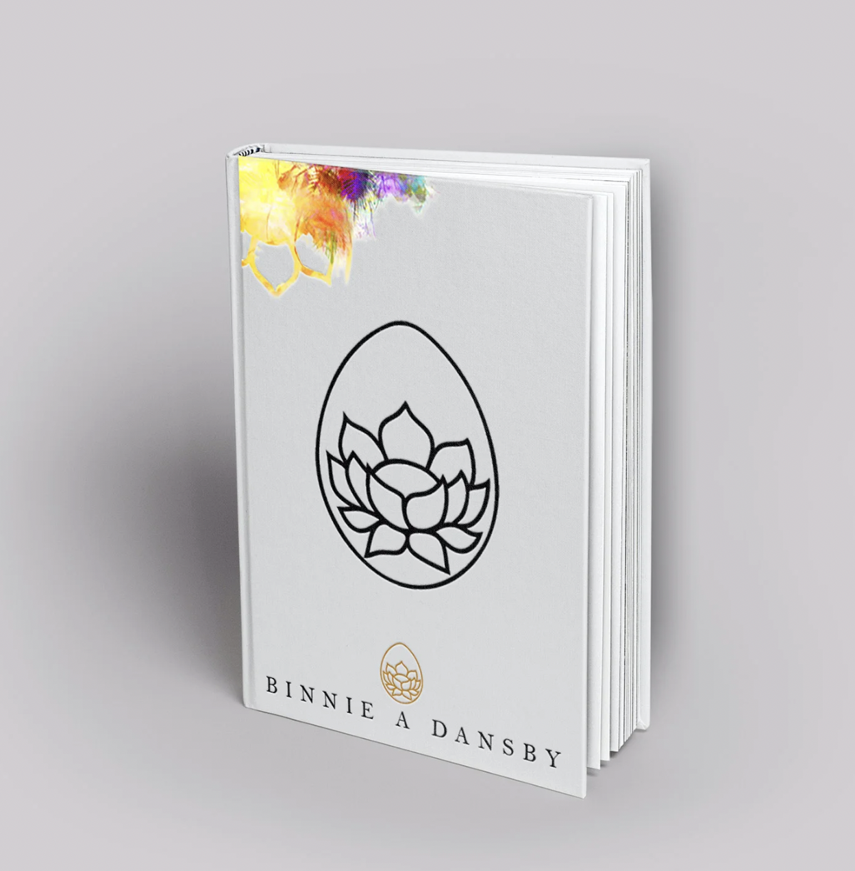 A white book with a black outline of a lotus flower on the cover, and the name "Binnie A Dansby" at the bottom. The top left corner has colorful, abstract watercolor paint splashes.