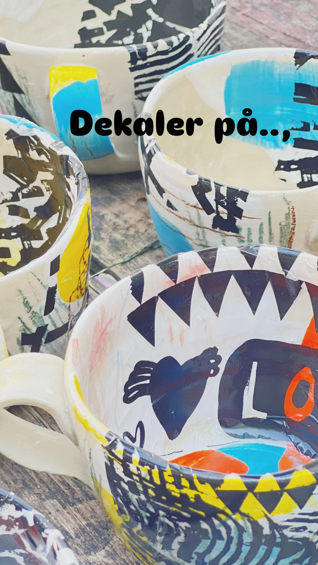 Färgglada handmålade krukor eller dekorerade muggar med olika mönster och figurer, står på ett träbord.