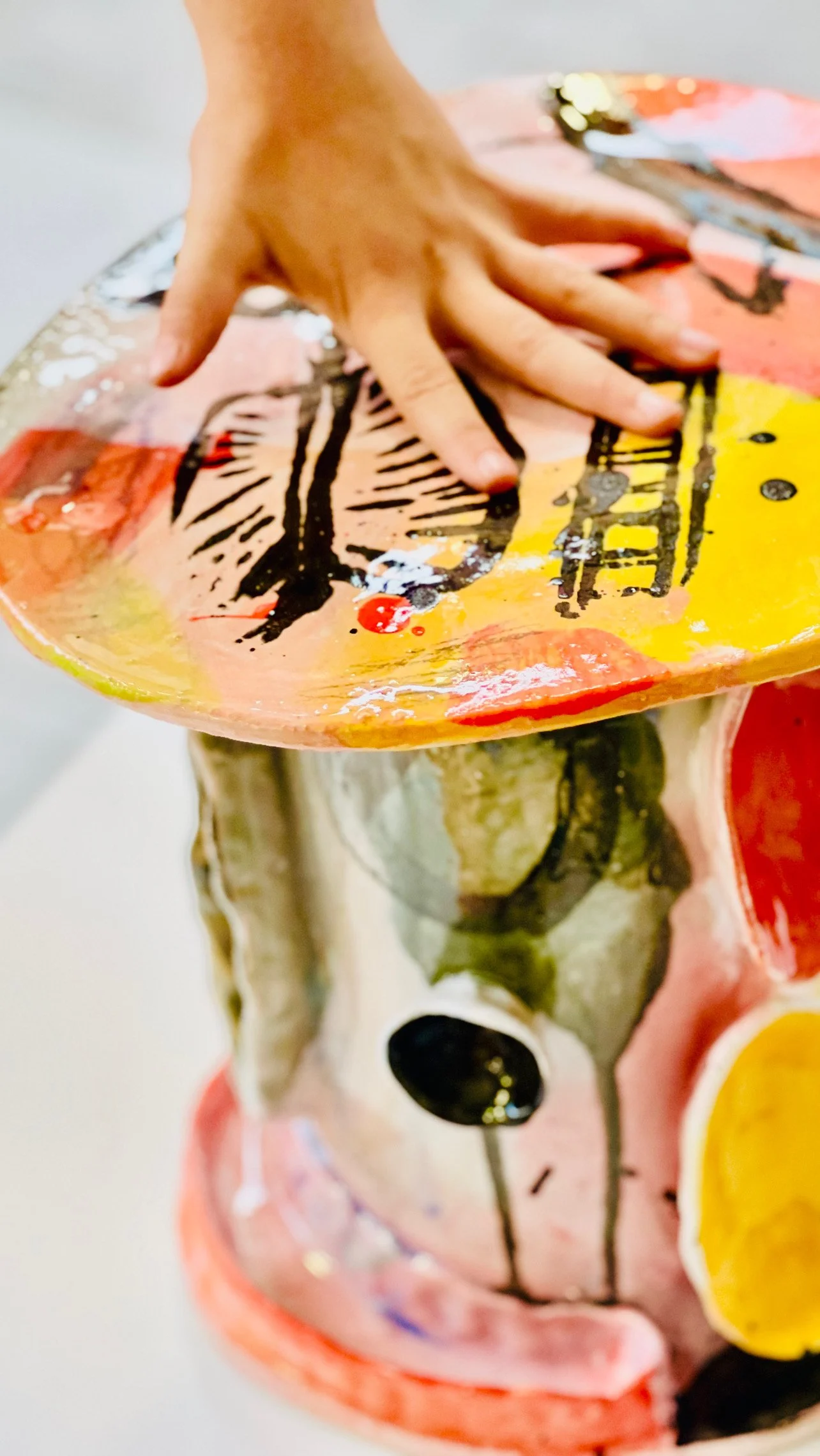 Färgglad keramikskulptur av ett ansikte, som är målat i ljusa färger med svarta detaljer.