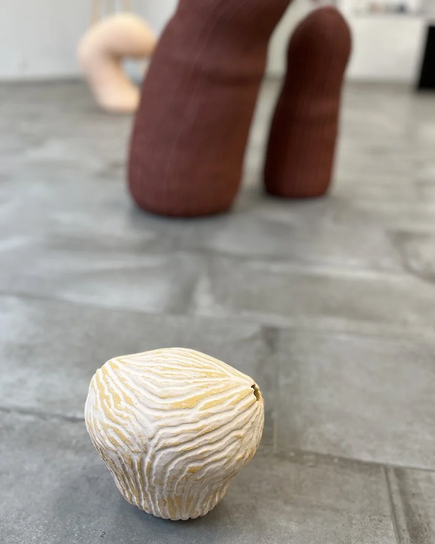 En boll av ost med gula och vita mönster, placerad på en grå cementgolv.