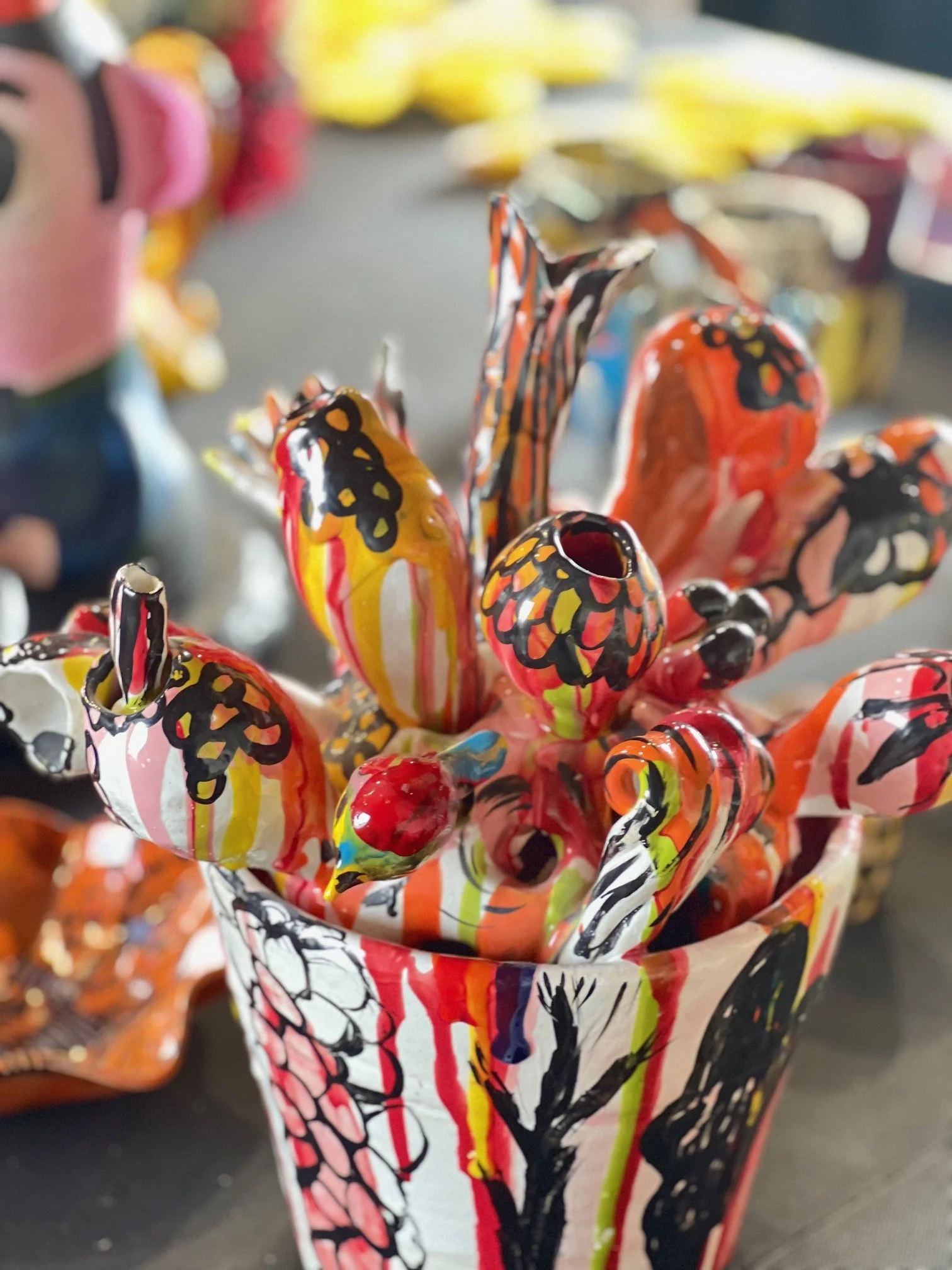 Färggrann konstgjord blomma av keramik i en vas.