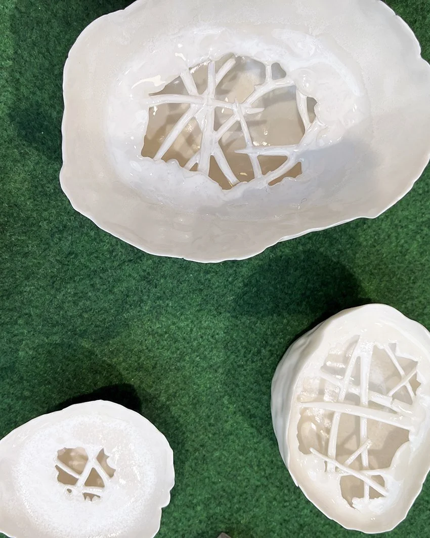 Tre vita plastskalsmider med lösa skär i mitten, placerade på en grön yta.