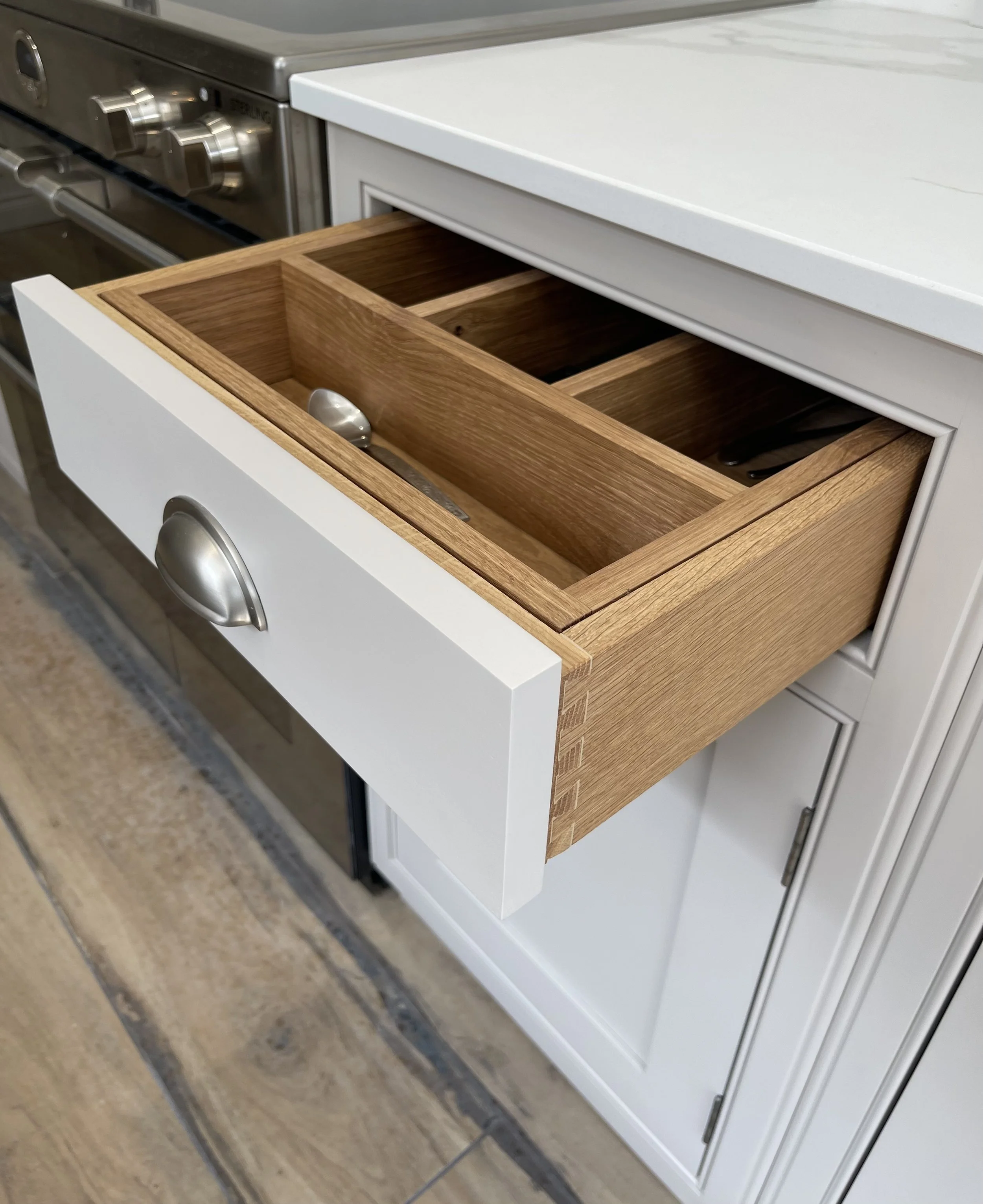 Bespoke kitchen drawer dovetailed with oak interior and dividers, containing cutlery and bespoke cabinetry.