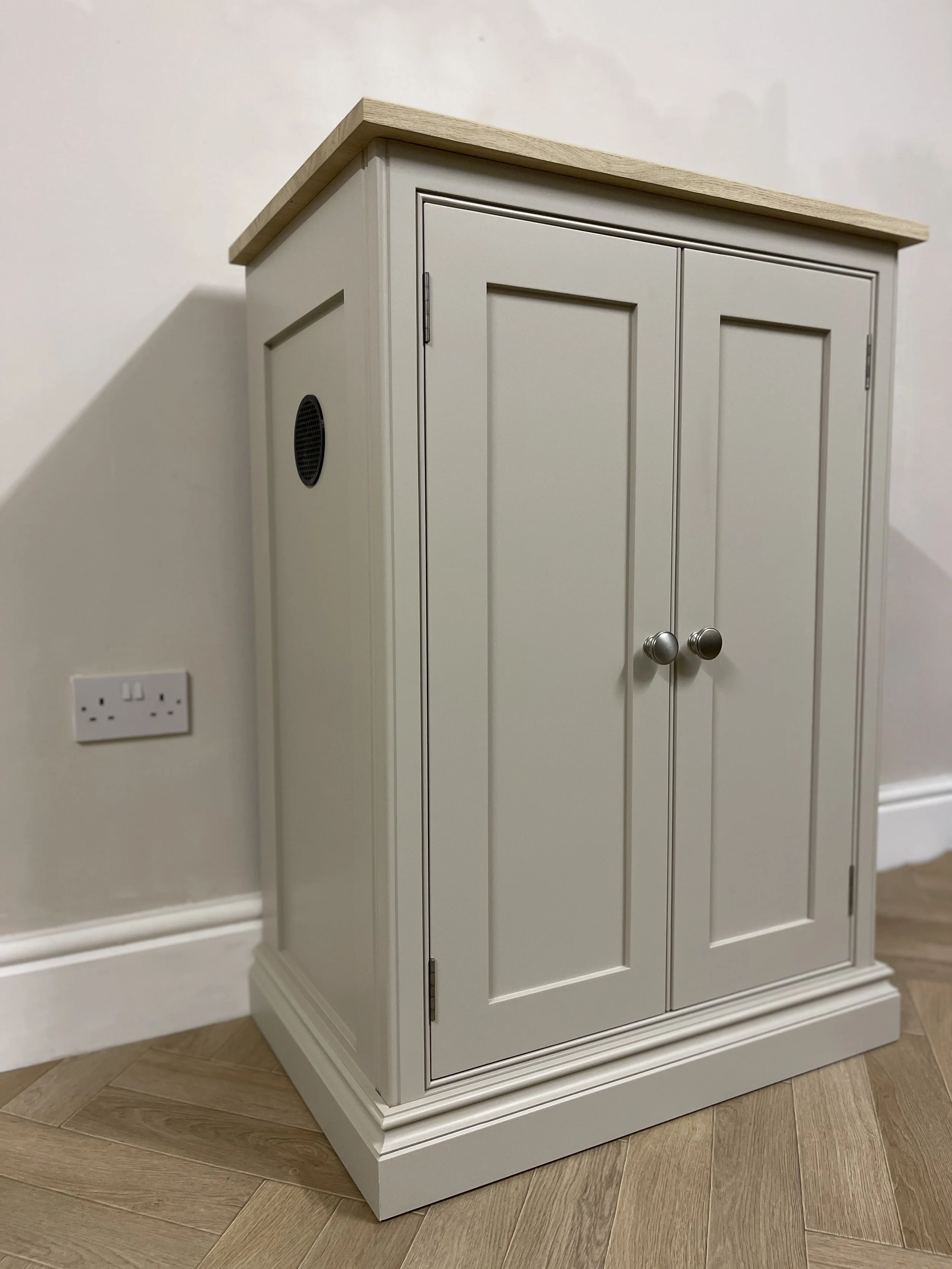 Bespoke hi-fi cabinet with two doors, polished chrome handles, and oak wooden top, standing on parquet floor.