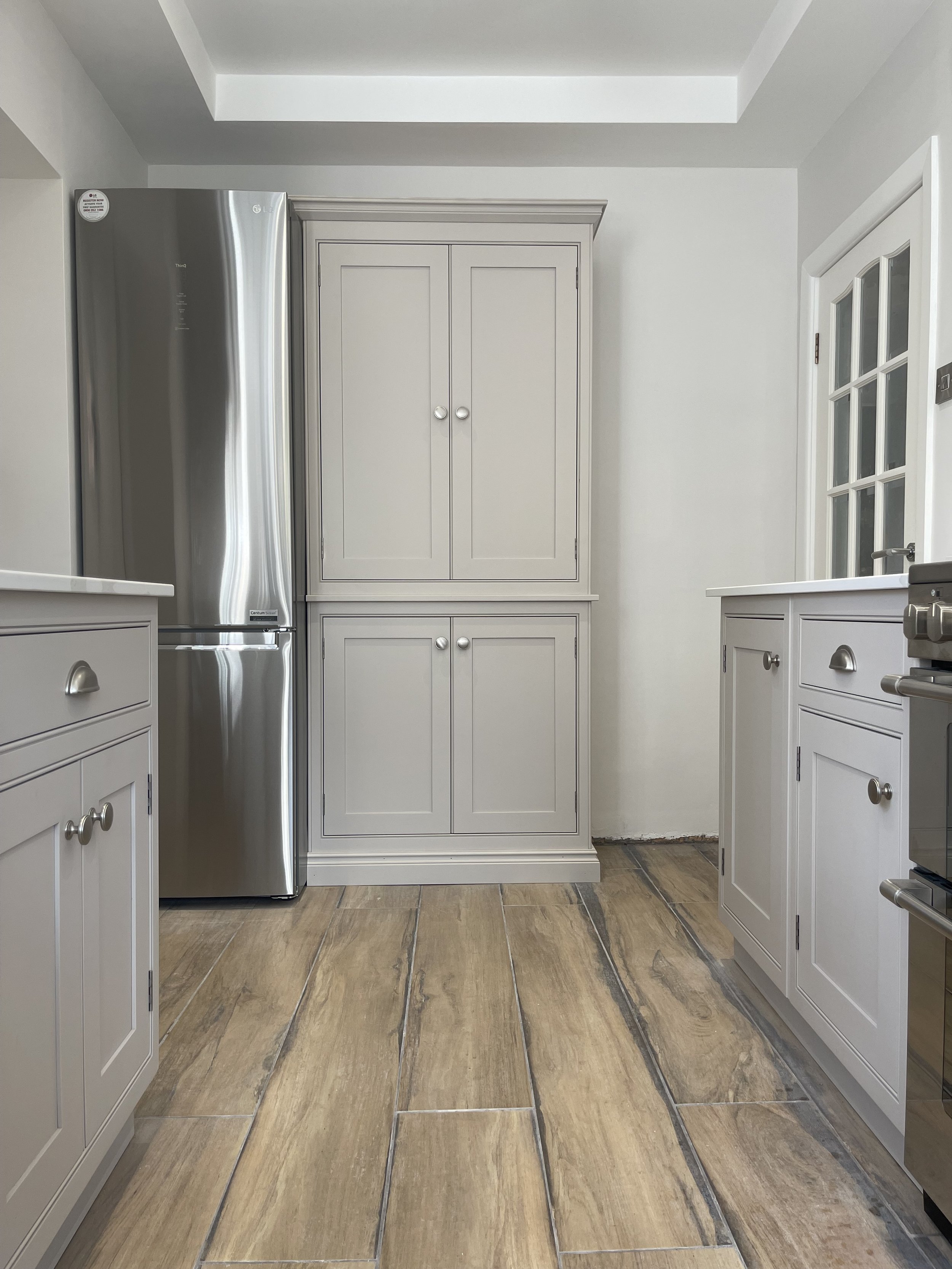 Handcrafted kitchen with grey cabinetry and stainless steel refrigerator