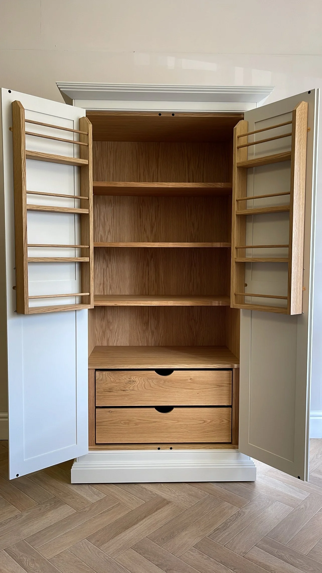 Handmade larder cupboard with oak shelves and oak drawers on herringbone floor.