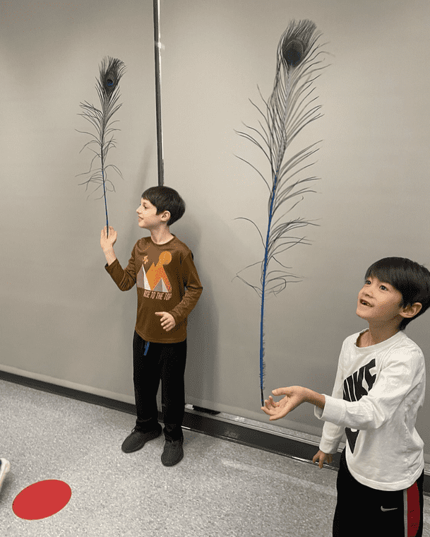 Two Children learning feather balancing at a summer circus skills workshop with Elevate Circus Workshops