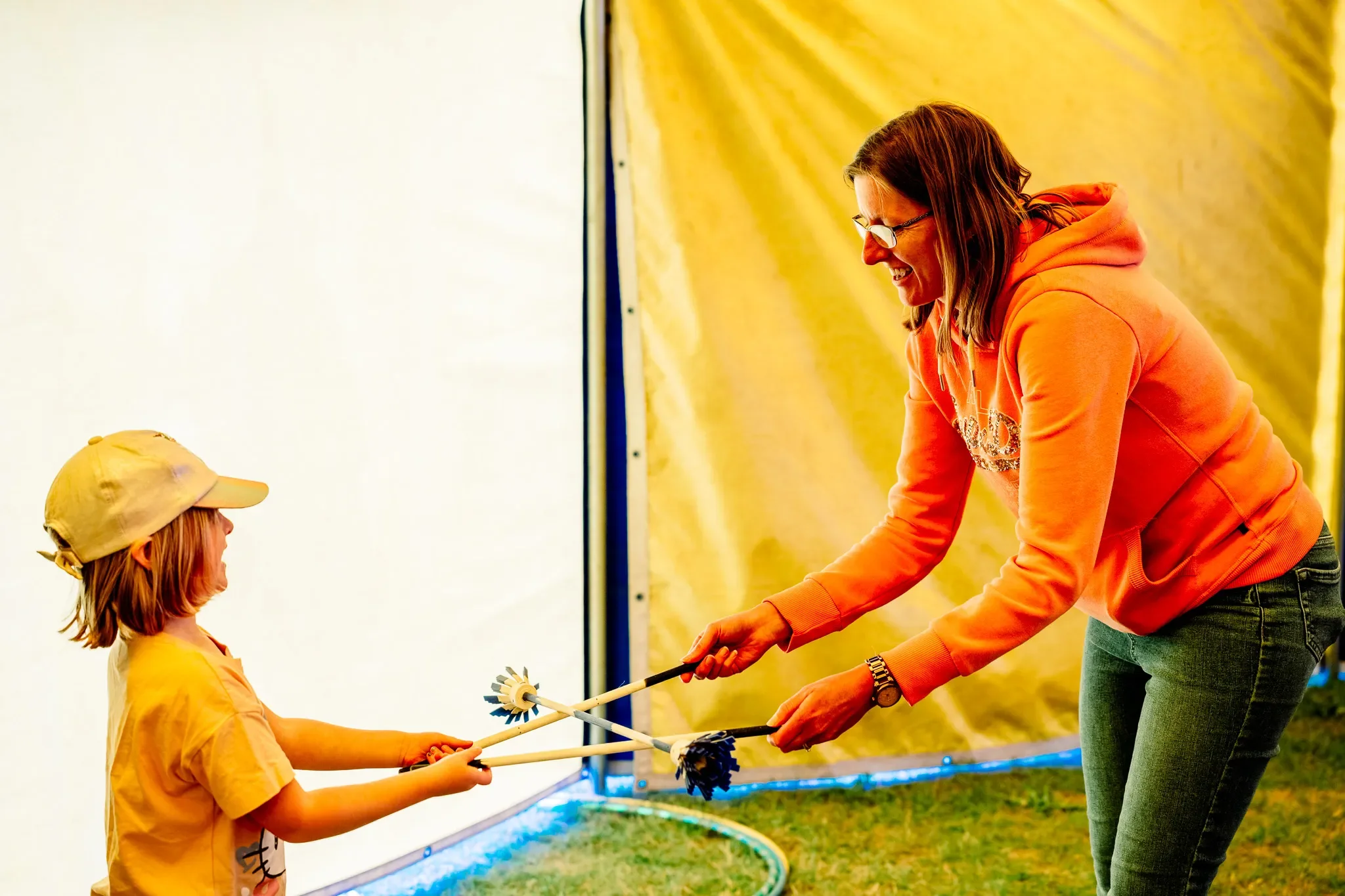 a young woman and child playing with flower sticks inside a circus tent