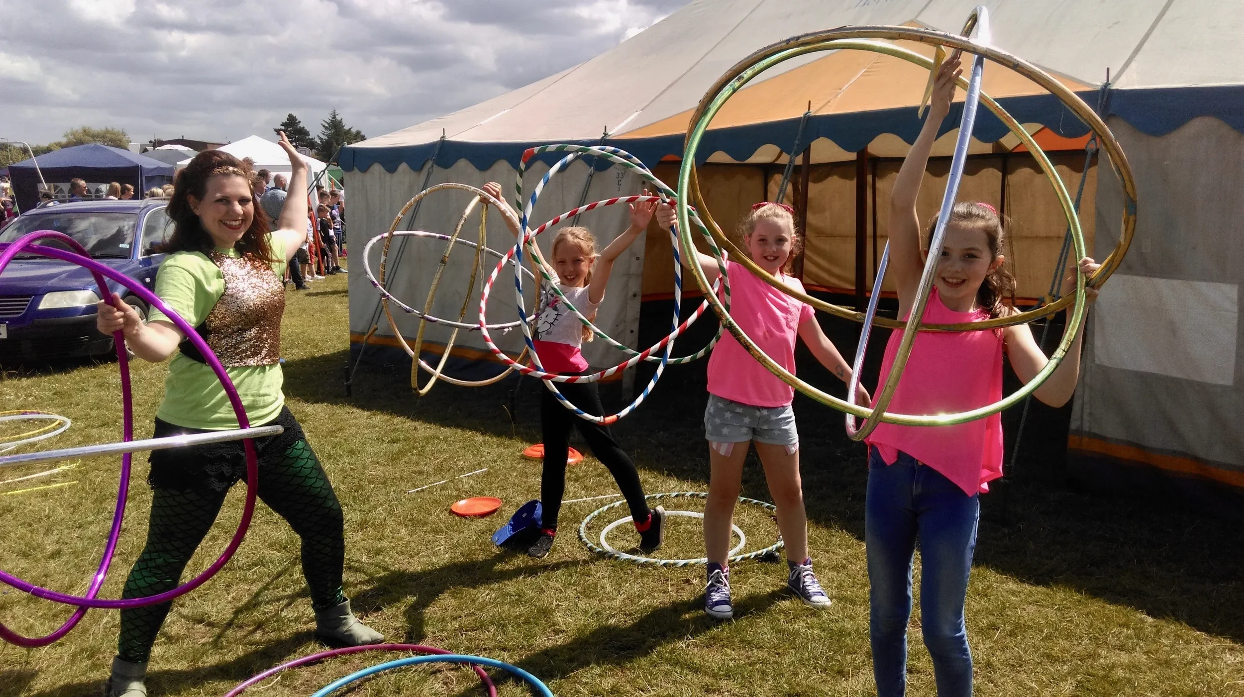 4 girls playing with hula hoops outside a circus tent