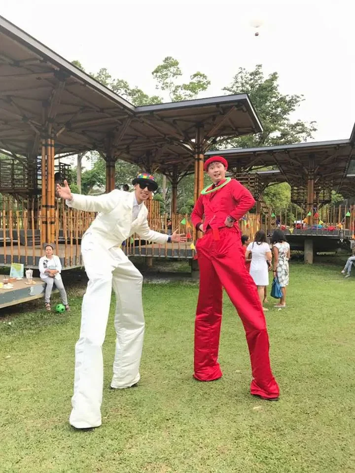 2 stilt walkers posing for the camera 1 dressed all in white and 1 all in red
