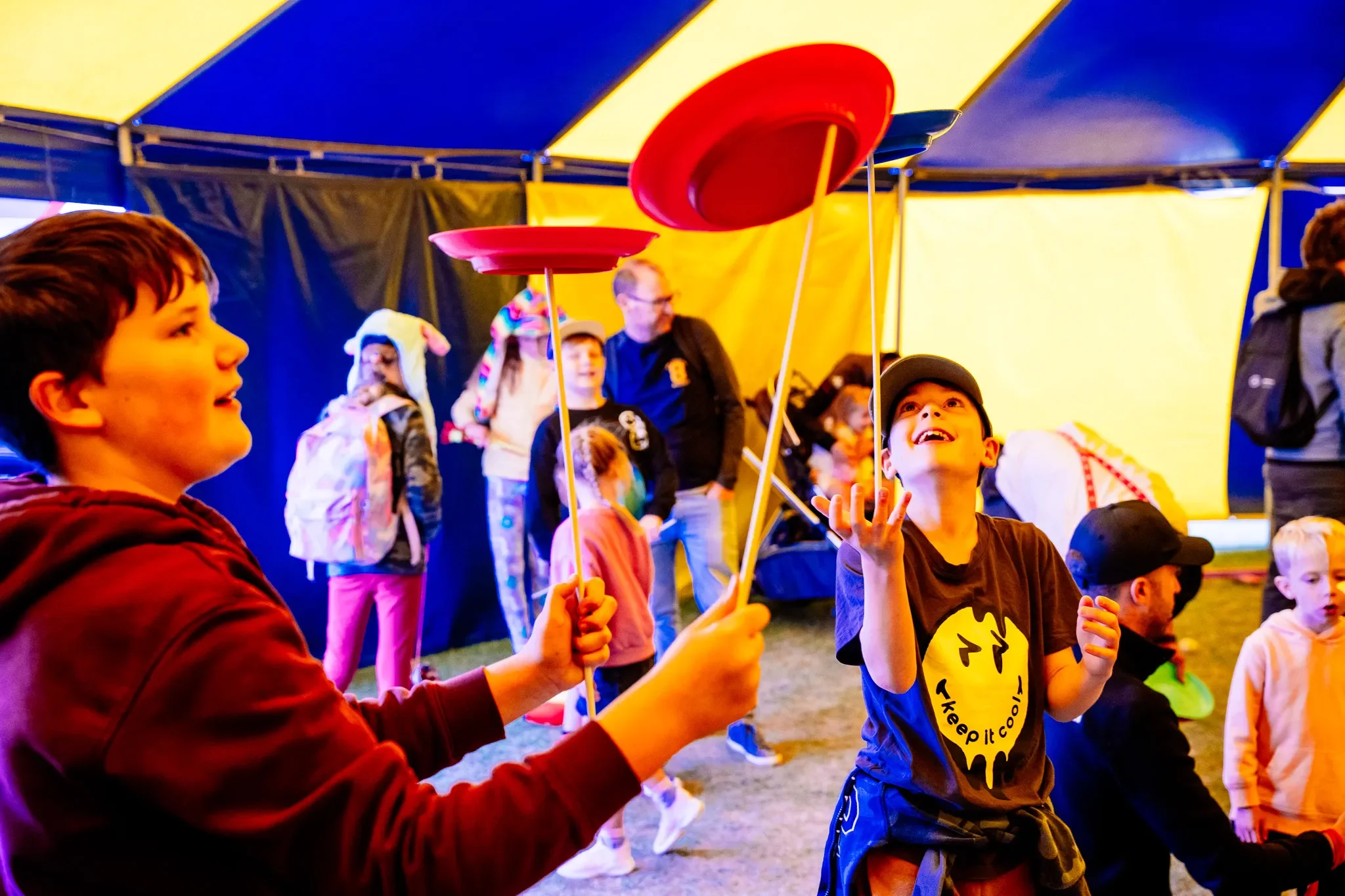 Children playing with spinning plates inside a colourful tent