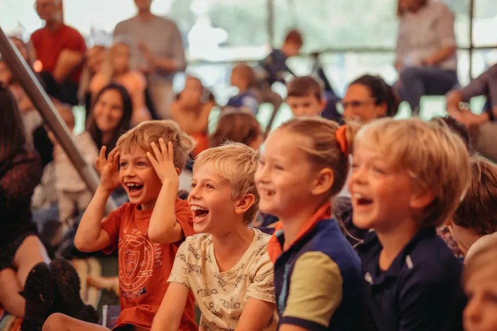 a group of laughing and happy children watching something to the left