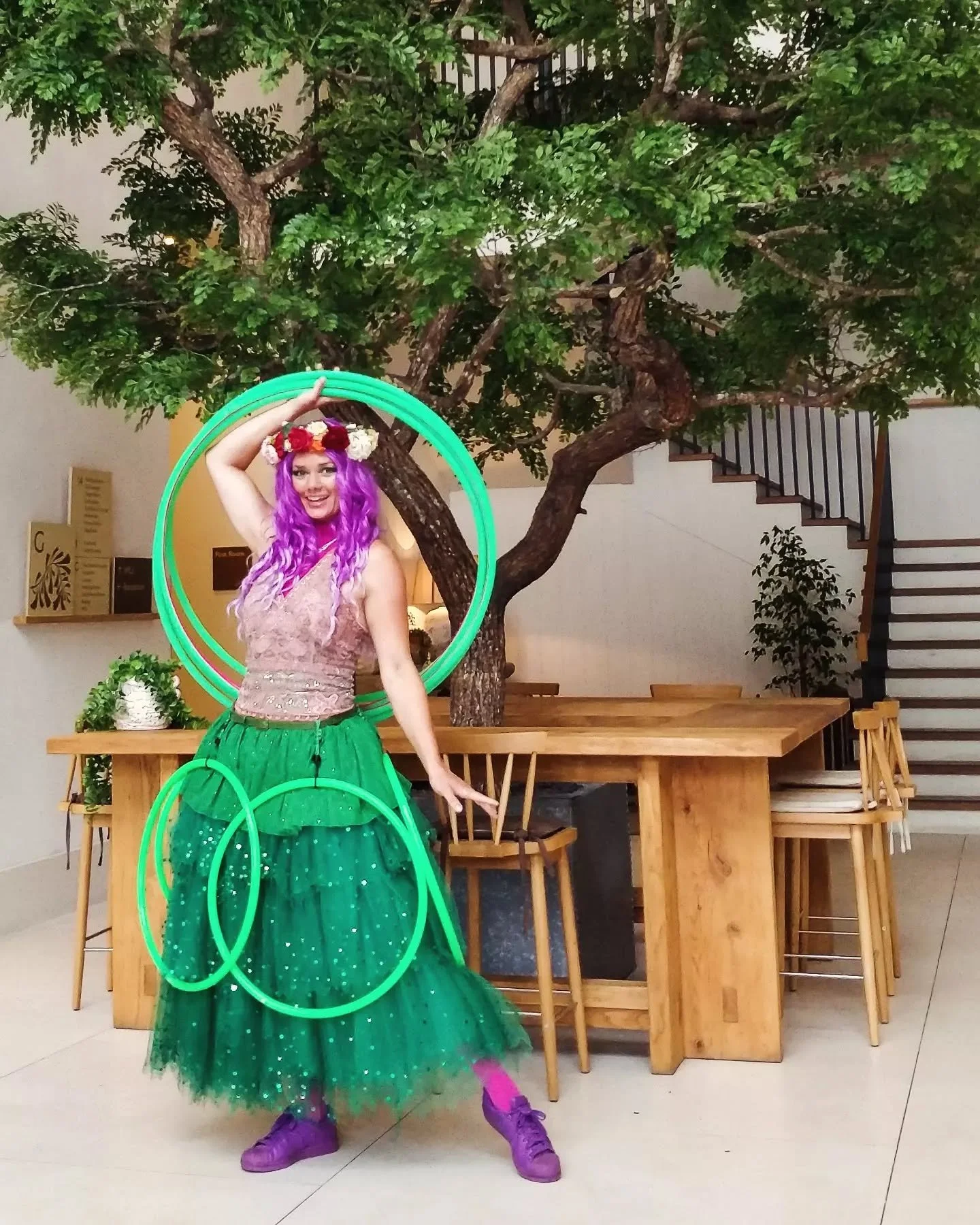 A female walkabout performer dressed like a green fairy carrying hola hoops