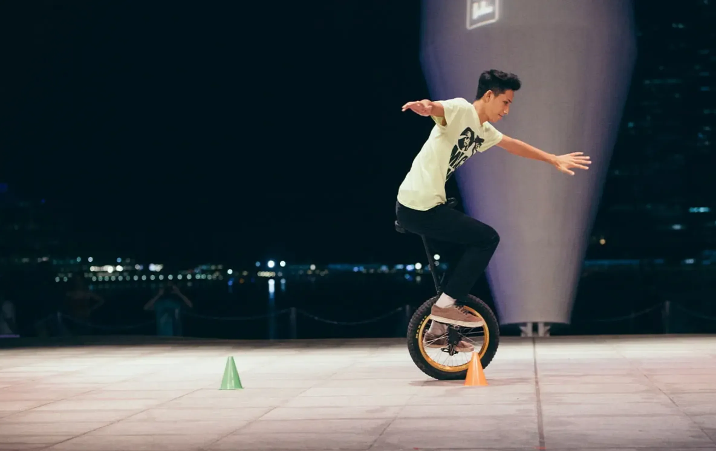 man riding unicycle around small cones on the ground