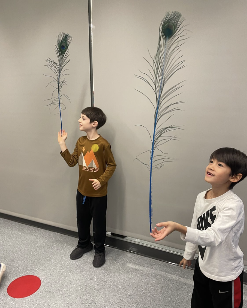 Two Children learning feather balancing at a summer circus skills workshop with Elevate Circus Workshops