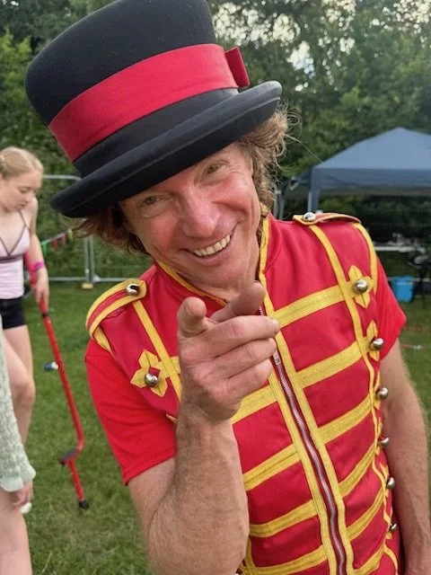 a performer in ringmaster costume pointing at the camera
