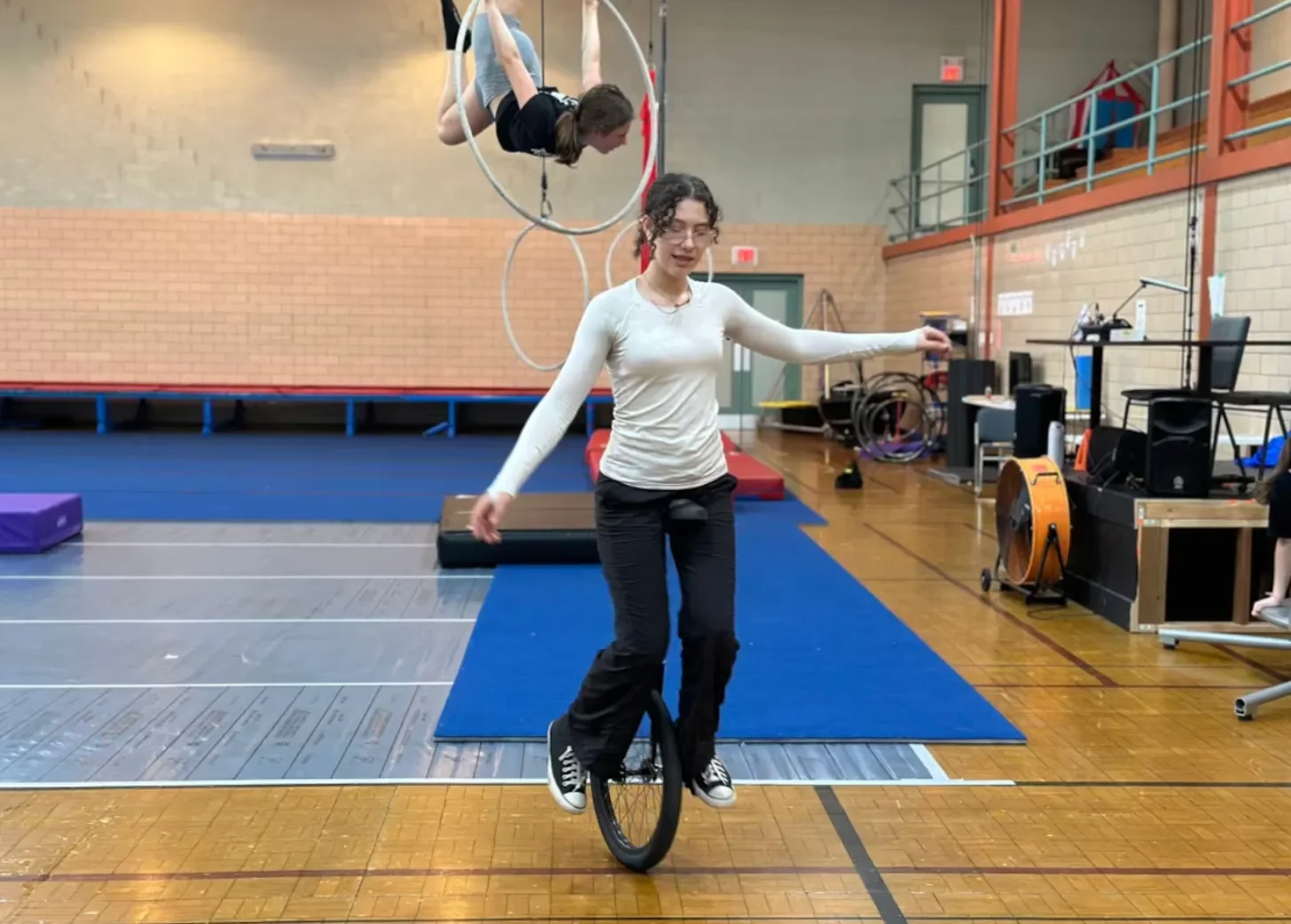 woman in a gymnasium practicing unicycling