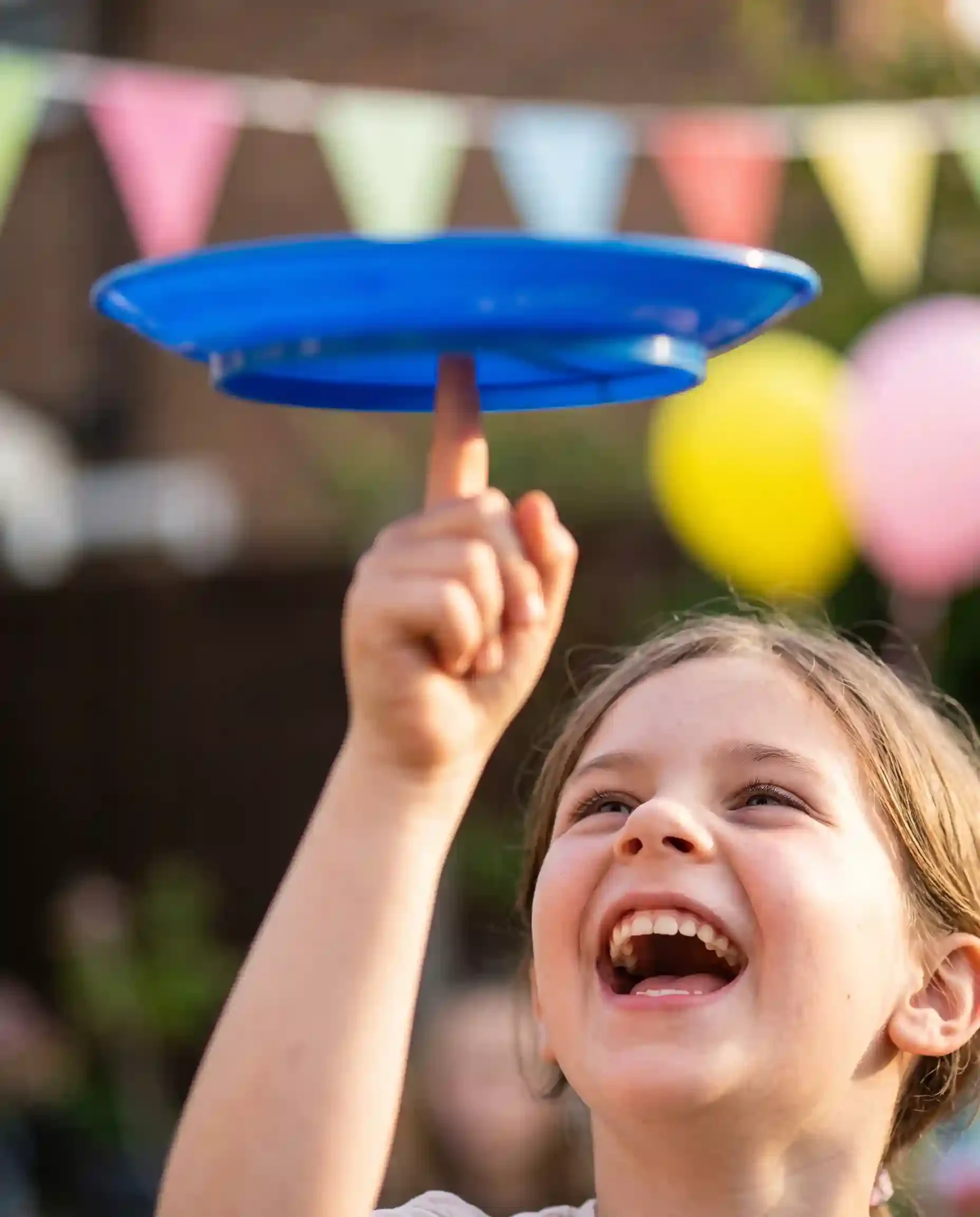 Child laughing while balancing a spinning circus plate on their fingertip at a party