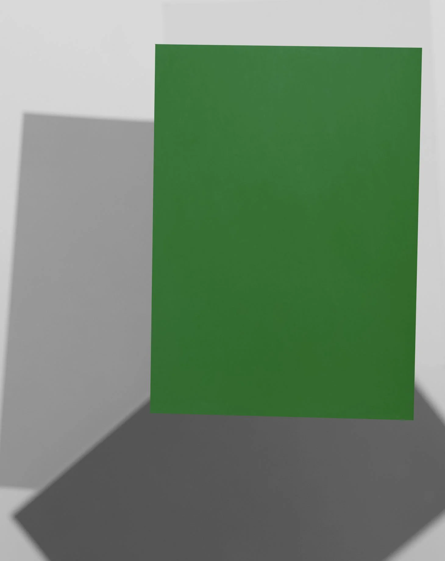 Green rectangular paper standing upright on a gray surface, casting a shadow.