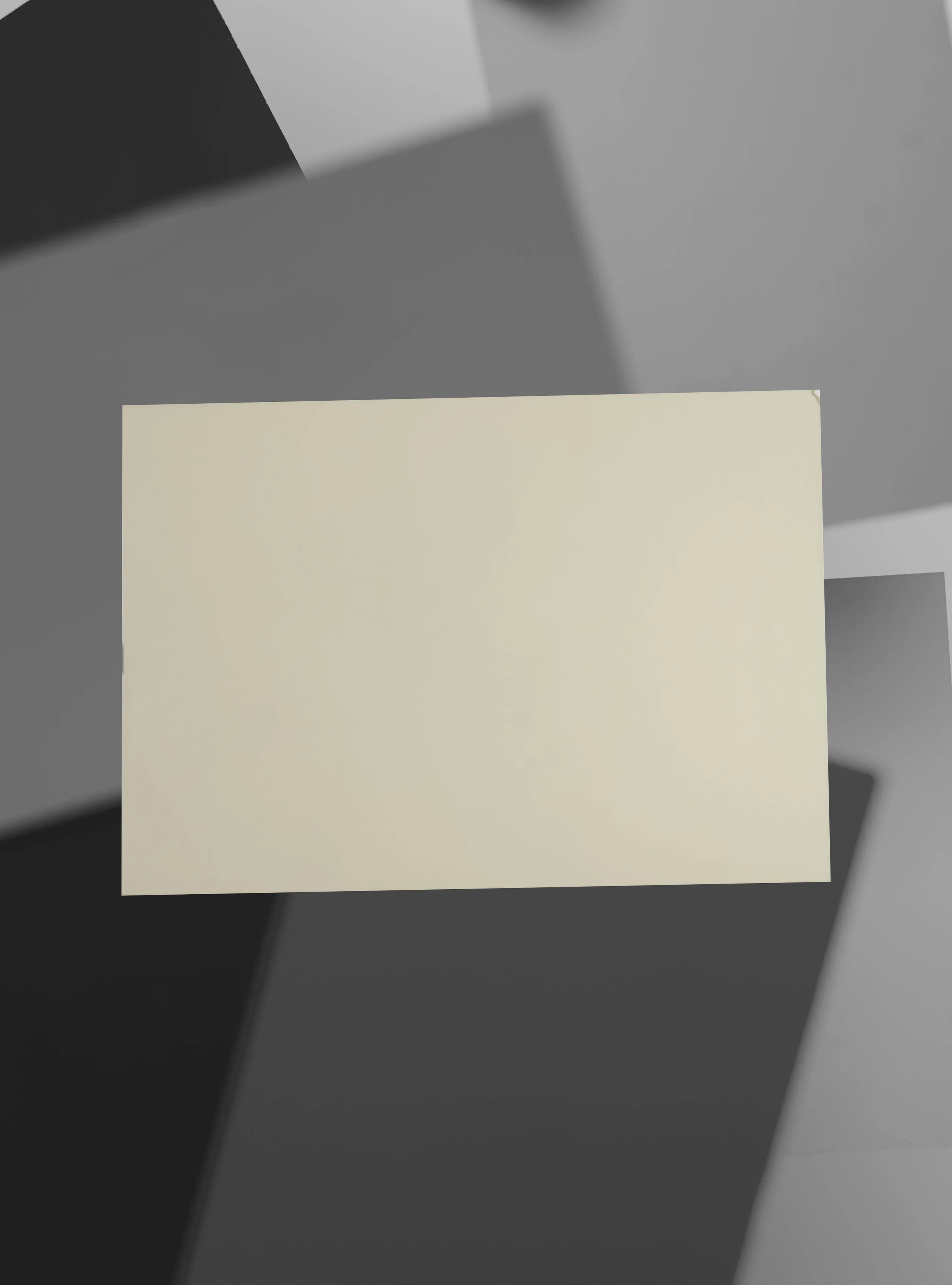 Close-up of a blank white sticky note on a dark surface with shadows playing across the background.