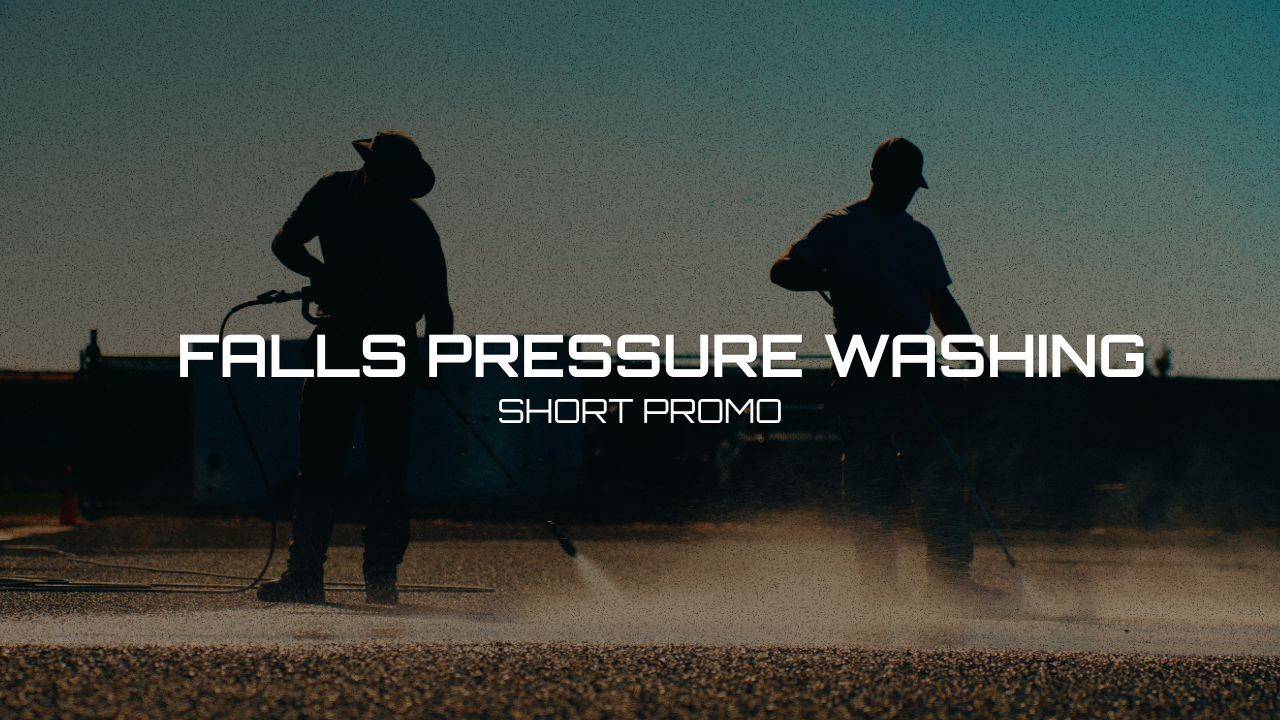 Two workers using pressure washers on a pavement, silhouetted against the sunset sky.